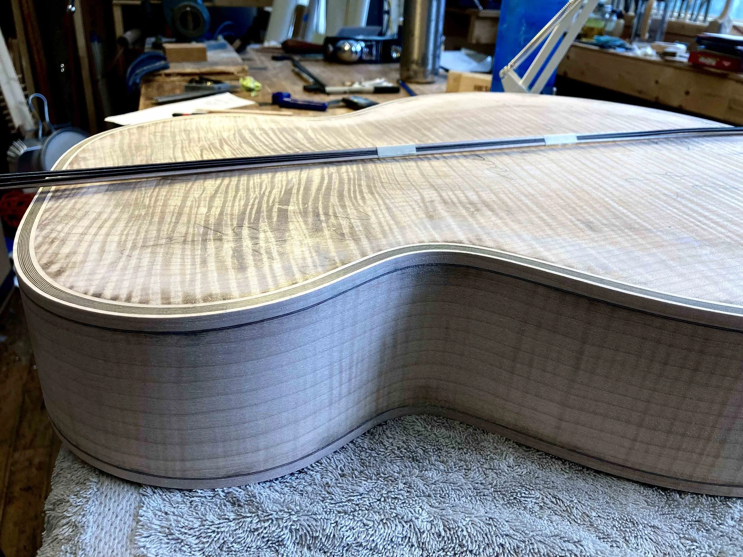 figured maple back on an acoustic guitar under construction in the queen city guitars shop in the northern new england town of brattleboro