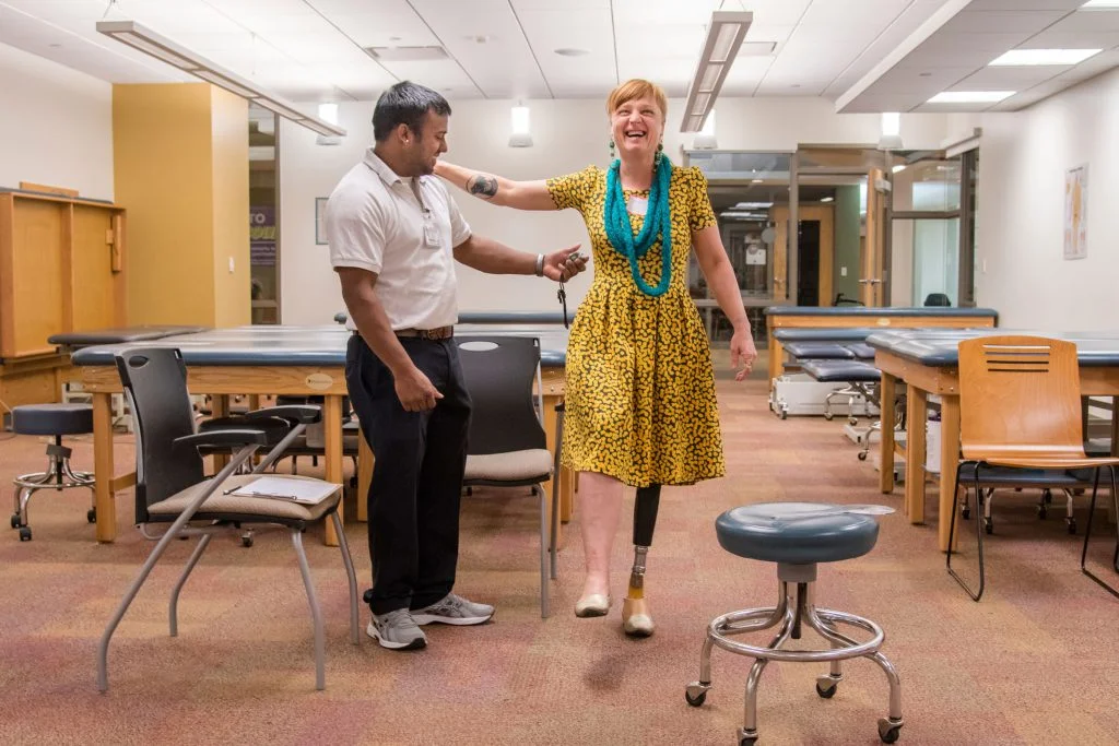 Shannon Jenkins, of Somerset, lets out a laugh while holding her balance with the aid of Chatham University physical therapy graduate student Brandon Maharaj. Maharaj was one of several physical therapists on hand to help evaluate women amputees.