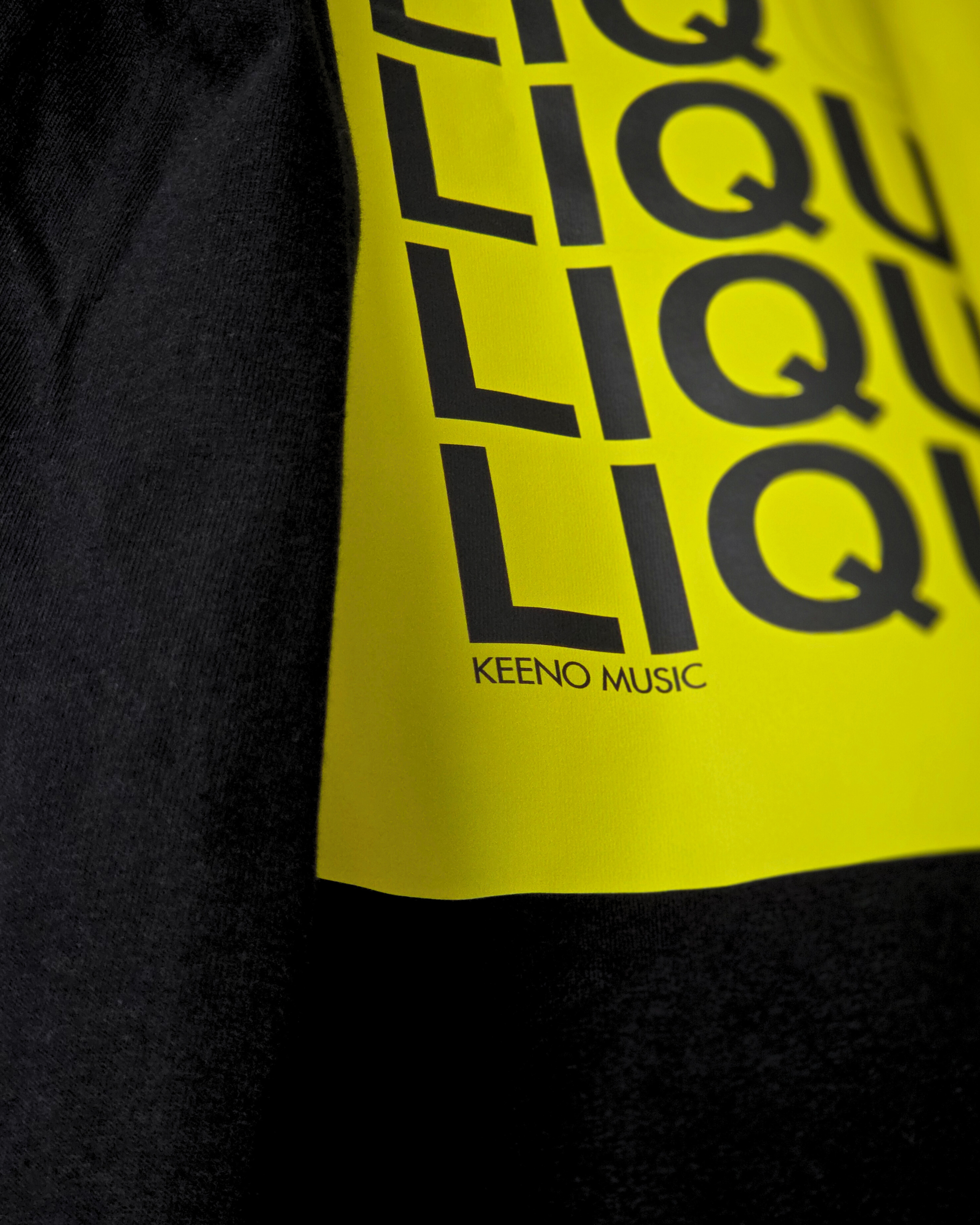 A yellow poster with black text that reads 'Y O U R' and 'L I Q U I D' and 'KEENO MUSIC' at the bottom, placed on a black fabric background.