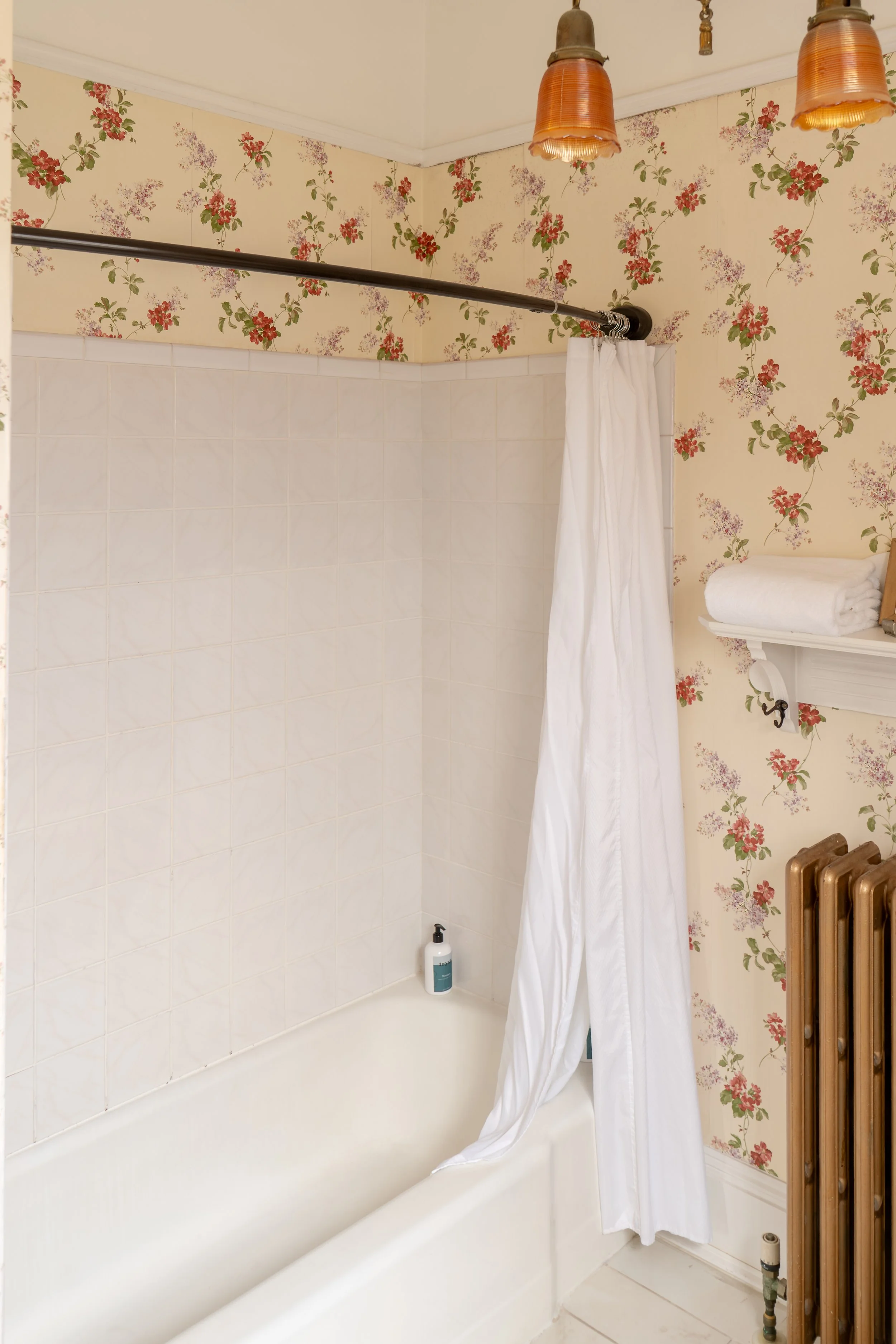 Bathroom shower in Room 2 at Water Street Inn with floral wallpaper and tub shower combination