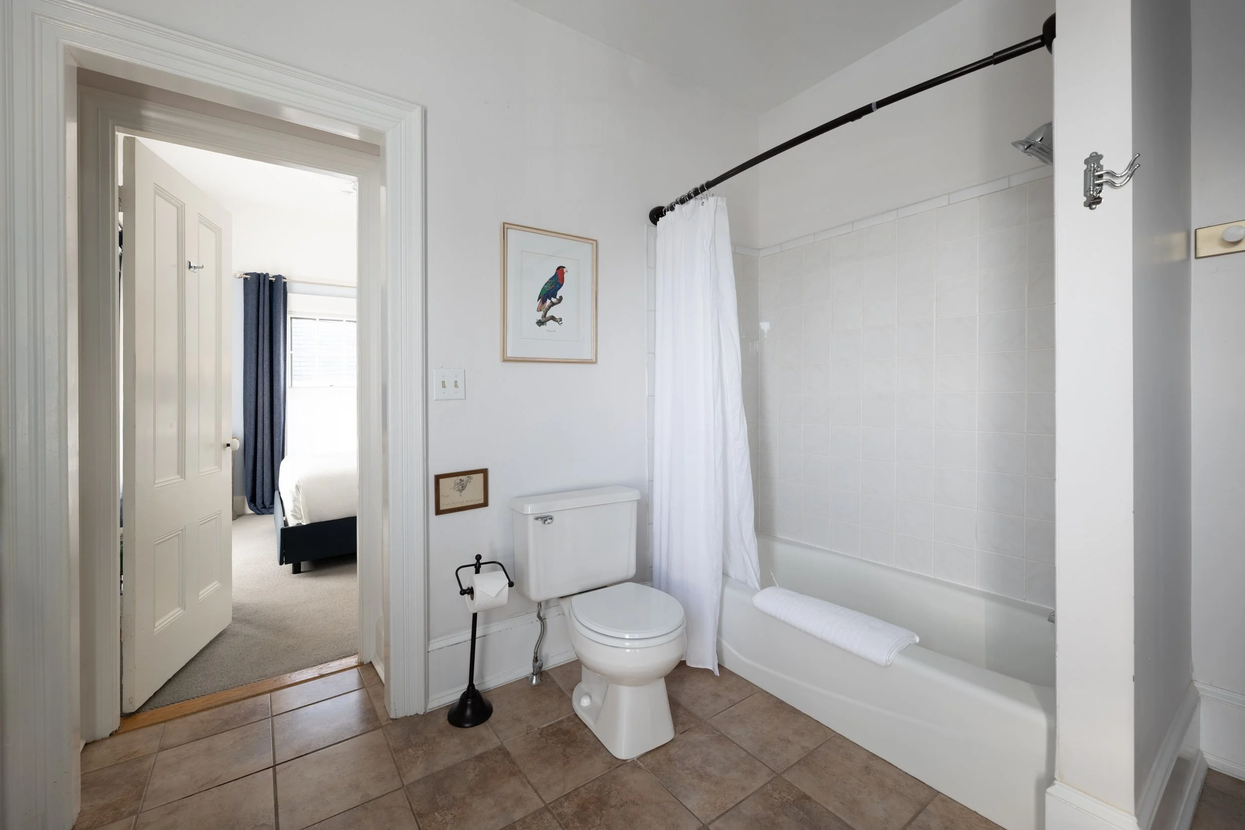 Bathroom in Room 4 at Water Street Inn with tub shower combination, tile flooring, and doorway to bedroom