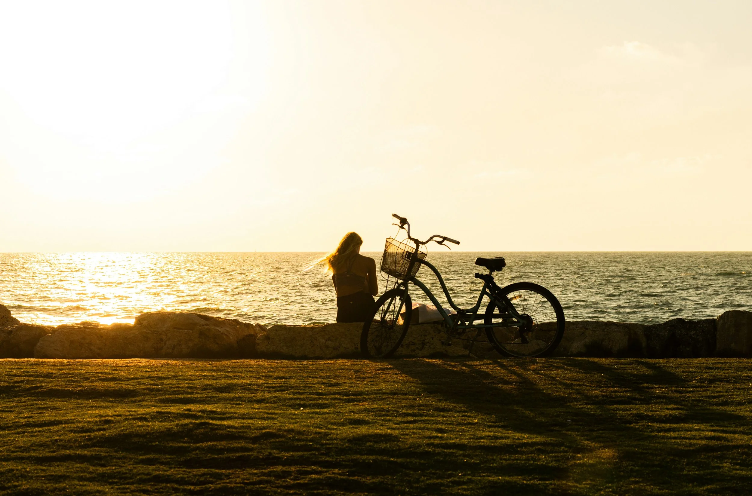 Cyclist relaxing by the ocean at sunset near Kittery Maine