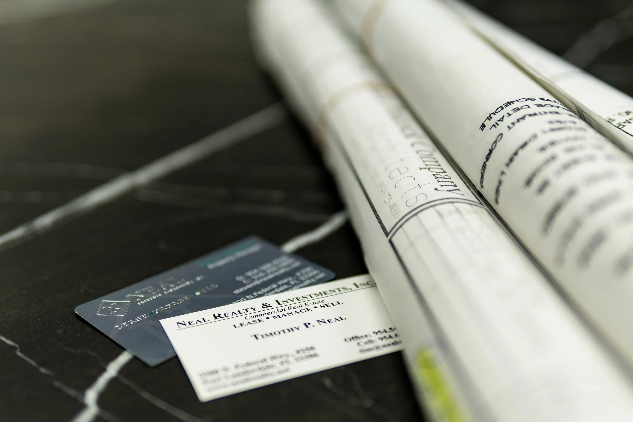 Neal Realty & Investments business cards beside commercial property plans