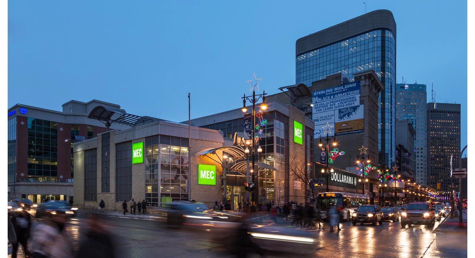  Mountain Equipment Co-op Winnipeg, exterior photo of building at dusk with pedestrians and cars in foreground / Photo:  Lindsay Reid  