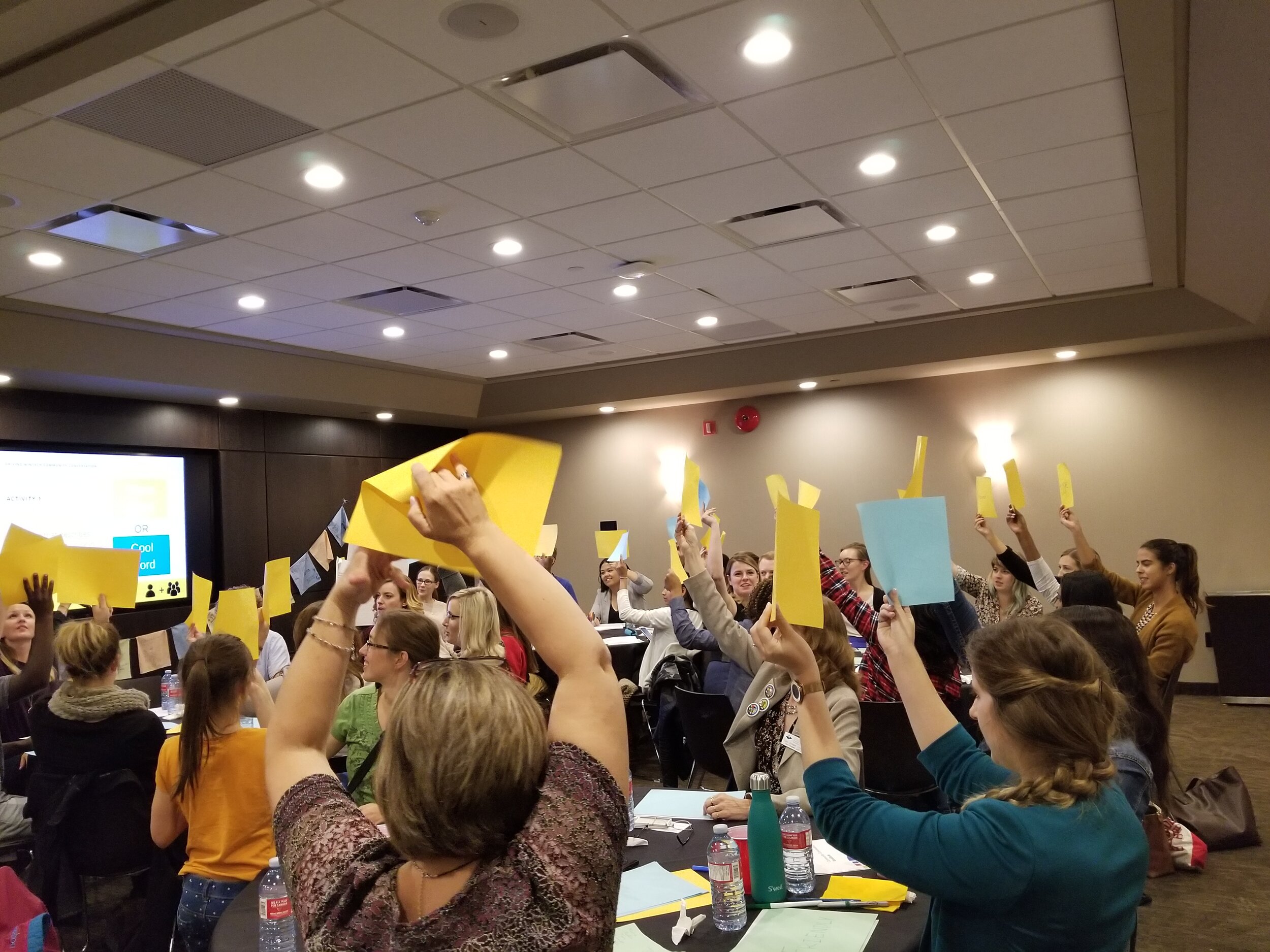  Community Conversation participants hold up pieces of paper that have their ideas on them. 