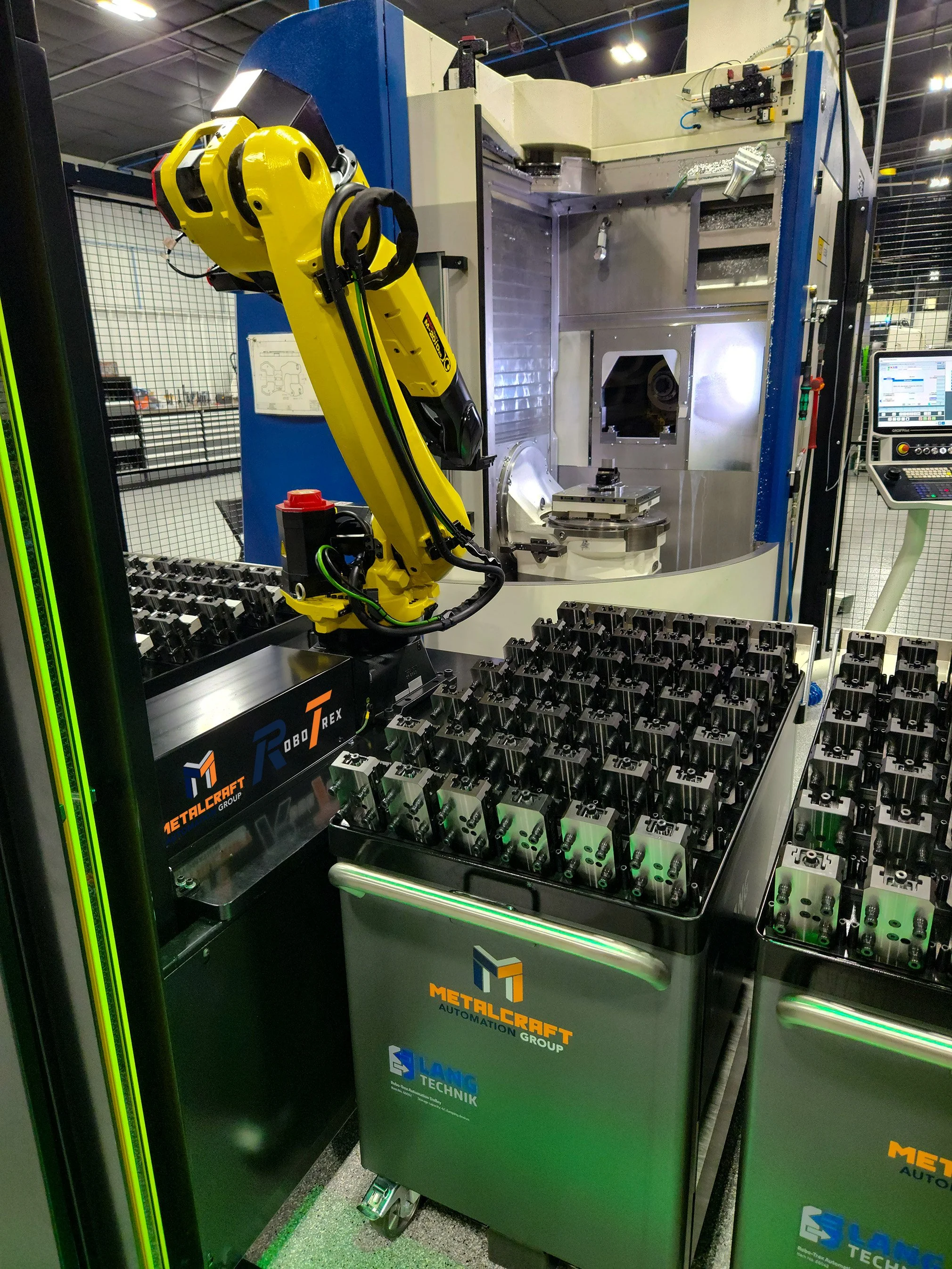 A view of the RoboTrex machine tending robot arm. There are multiple cartridges in a console next to the arm.