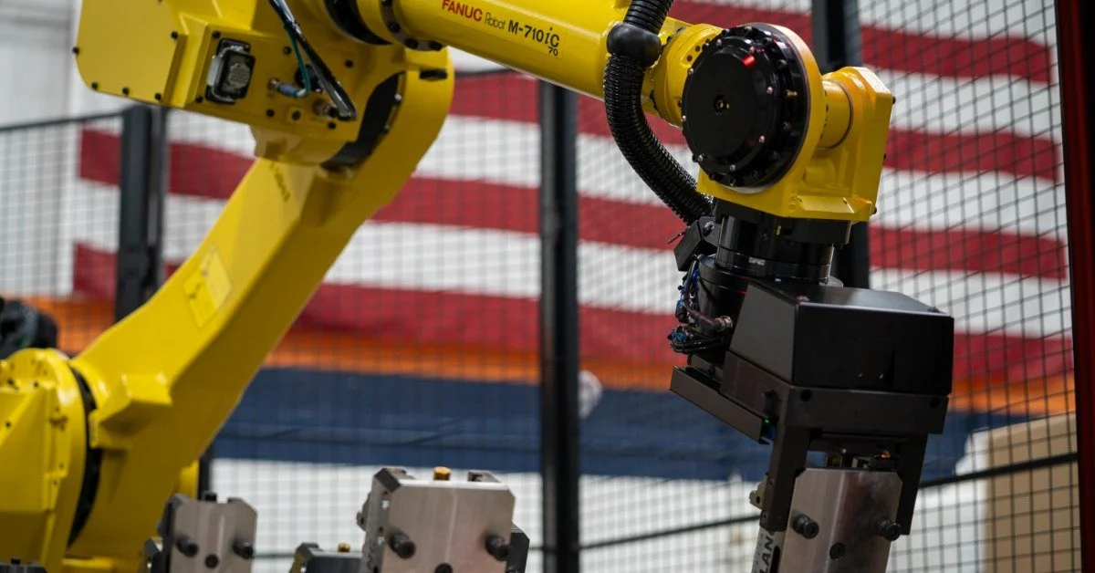 A yellow metal arm with an American flag in the background. The hand of the arm is out of frame and obscured.