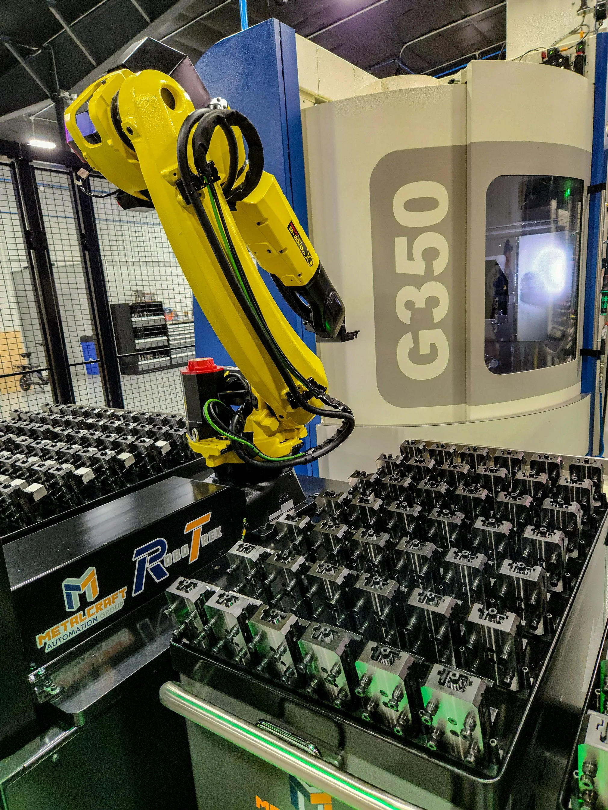 A large, yellow robotic arm used for assembly line automation positioned next to several metallic structures.