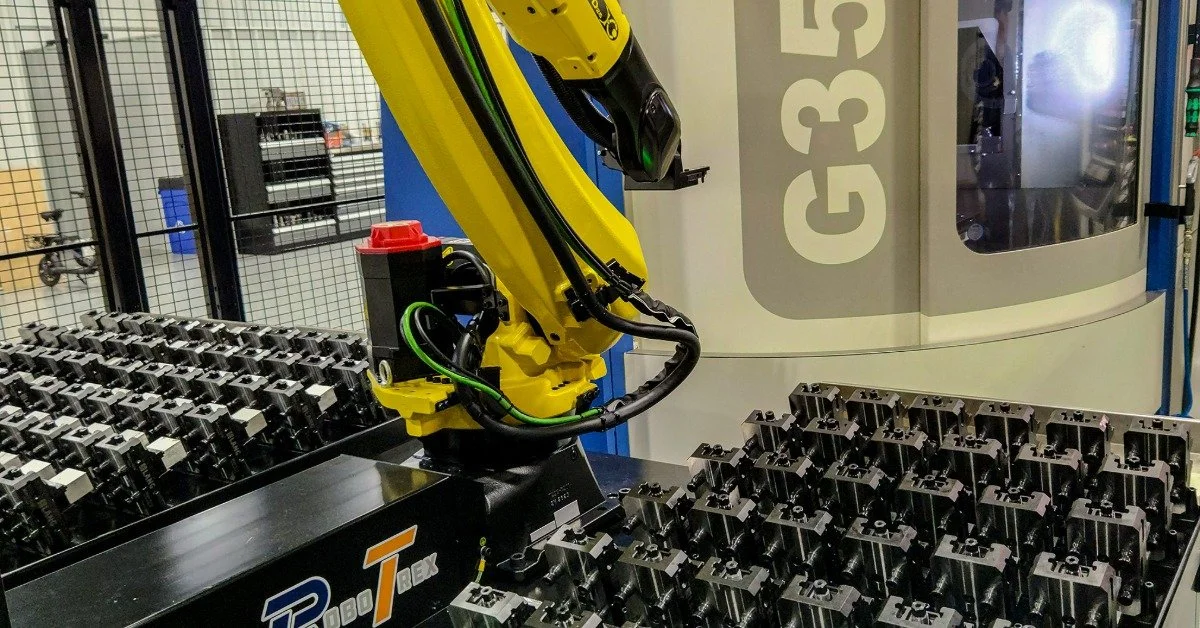 A large and yellow robotic arm set up next to a console. There is a large machine just behind the arm.