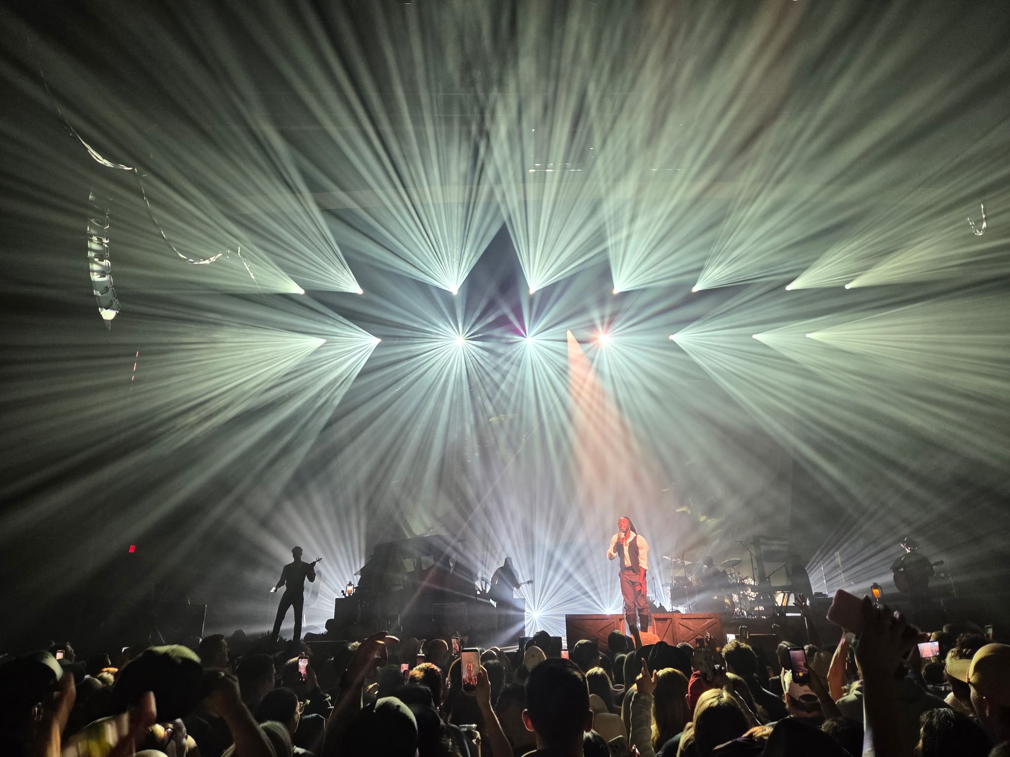 White beams of concert lighting spreading across the crowd during Shaboozey's performance at MGM Music Hall at Fenway.