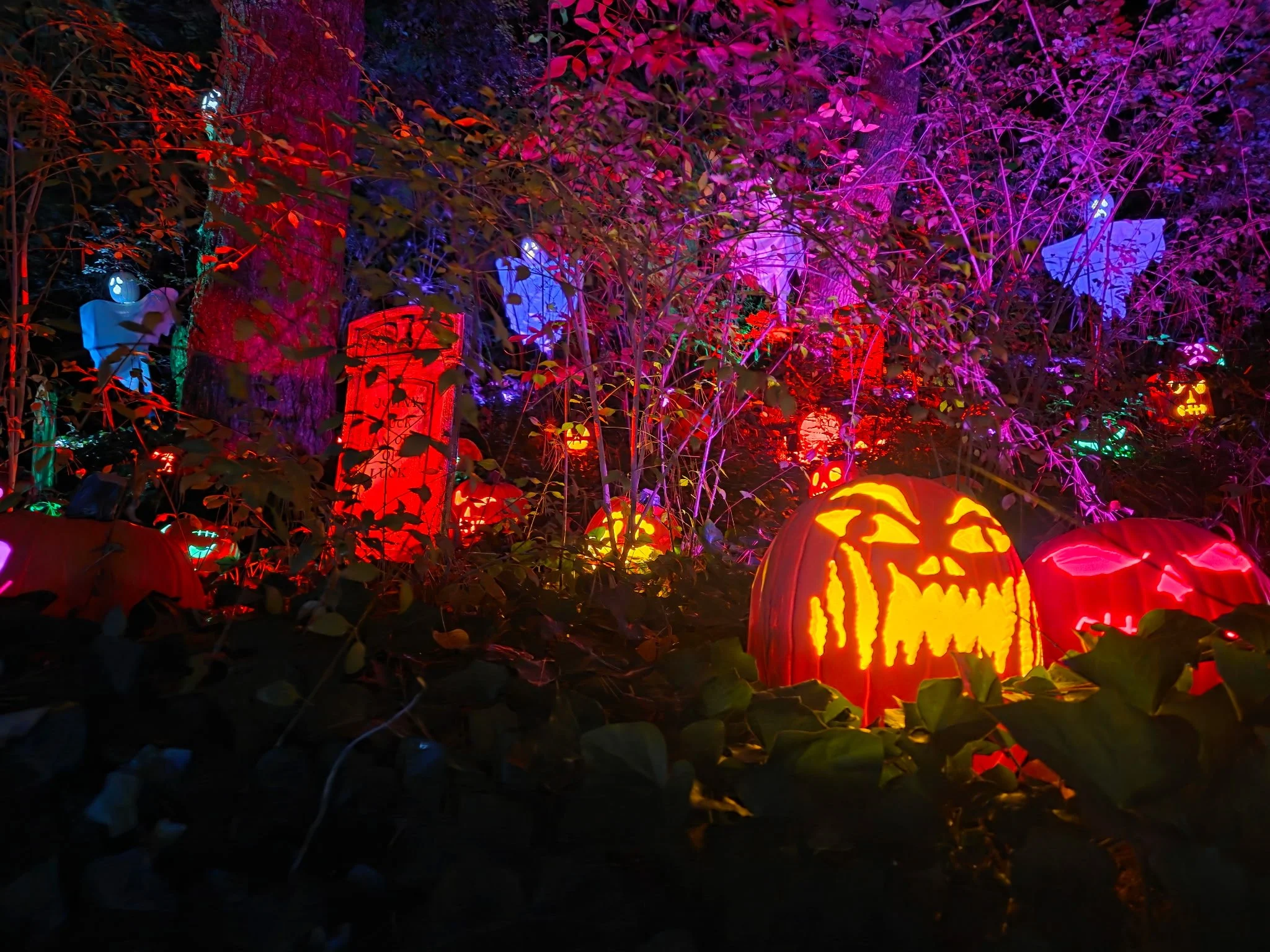 Glowing jack-o'-lanterns, tombstones, and floating ghosts create a spooky woodland scene.