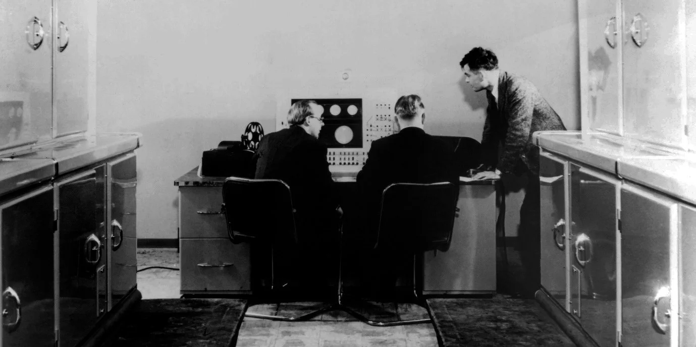 Figure 3. Alan Turing (right) and two Ferranti managers in a publicity shot for the new Ferranti Mark I. (c) Ferranti, 1951, but current copyright holder unknown. Copyright claims have been made by the University of Manchester and the Science Museum Group in the past but I doubt these can be for the underlying image.