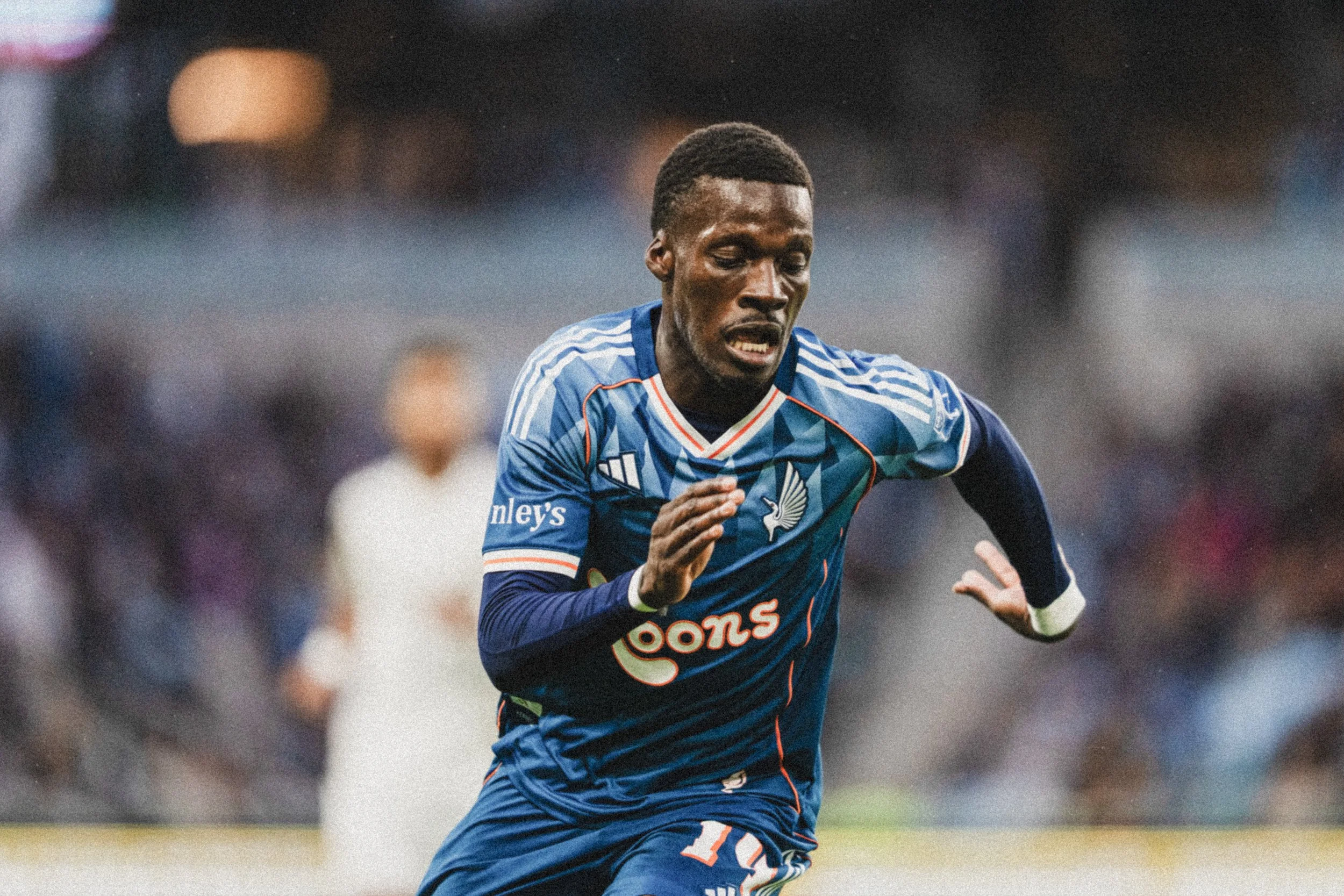 A soccer player in a blue uniform running on the field during a game.