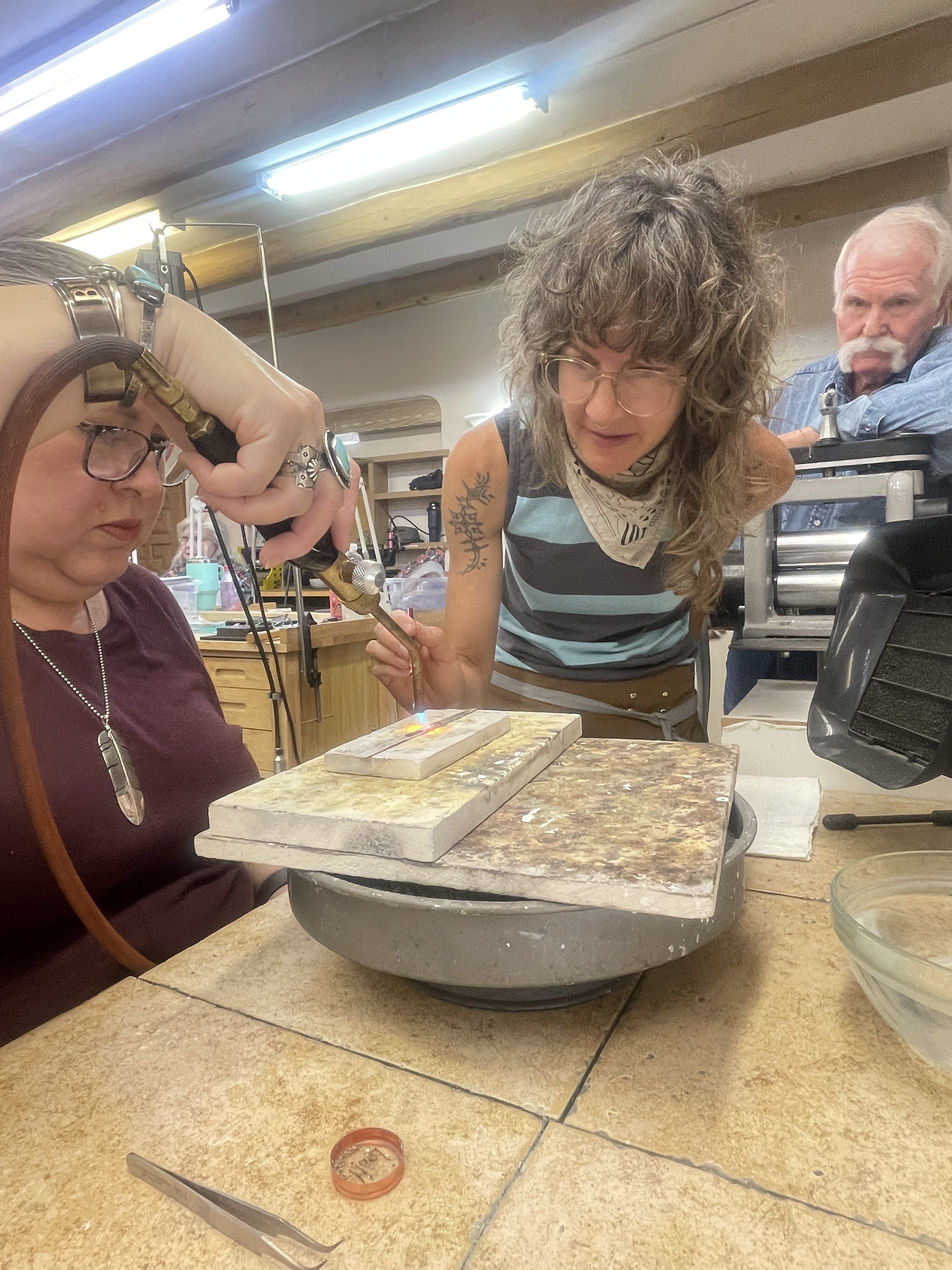 Instructor assisting with bezel setting during a jewelry class in Albuquerque