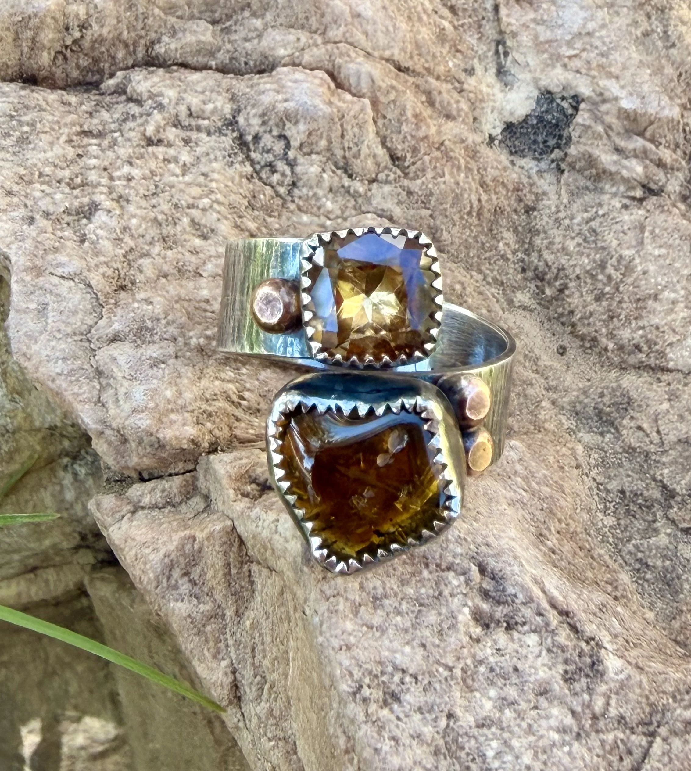 Finished sterling silver rings with green stones displayed on a bench during a silversmithing class in Albuquerque