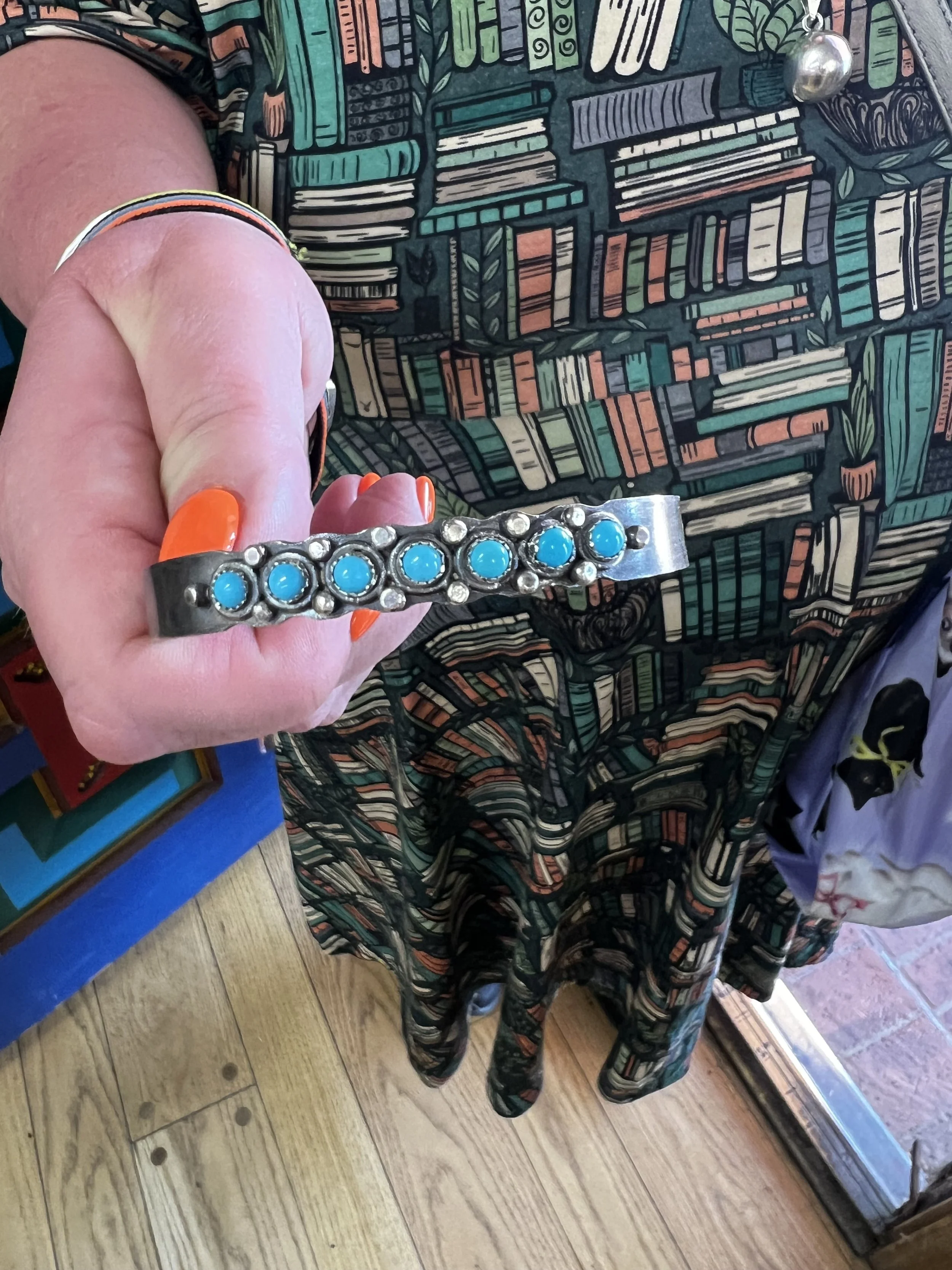 Hand holding a completed turquoise cuff from a jewelry making class in Albuquerque
