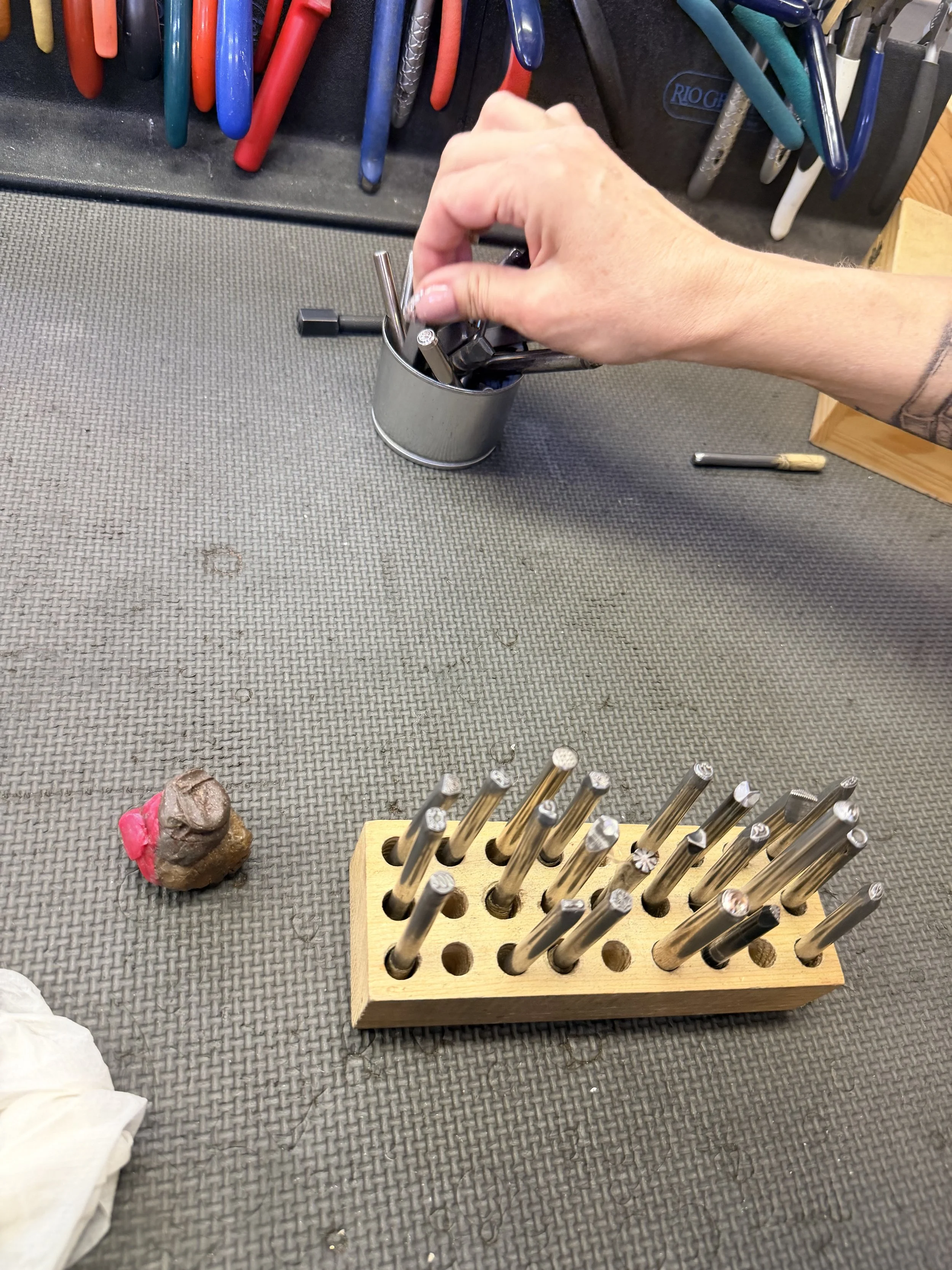 Student polishing a metal piece at the bench during a jewelry making class in Albuquerque.