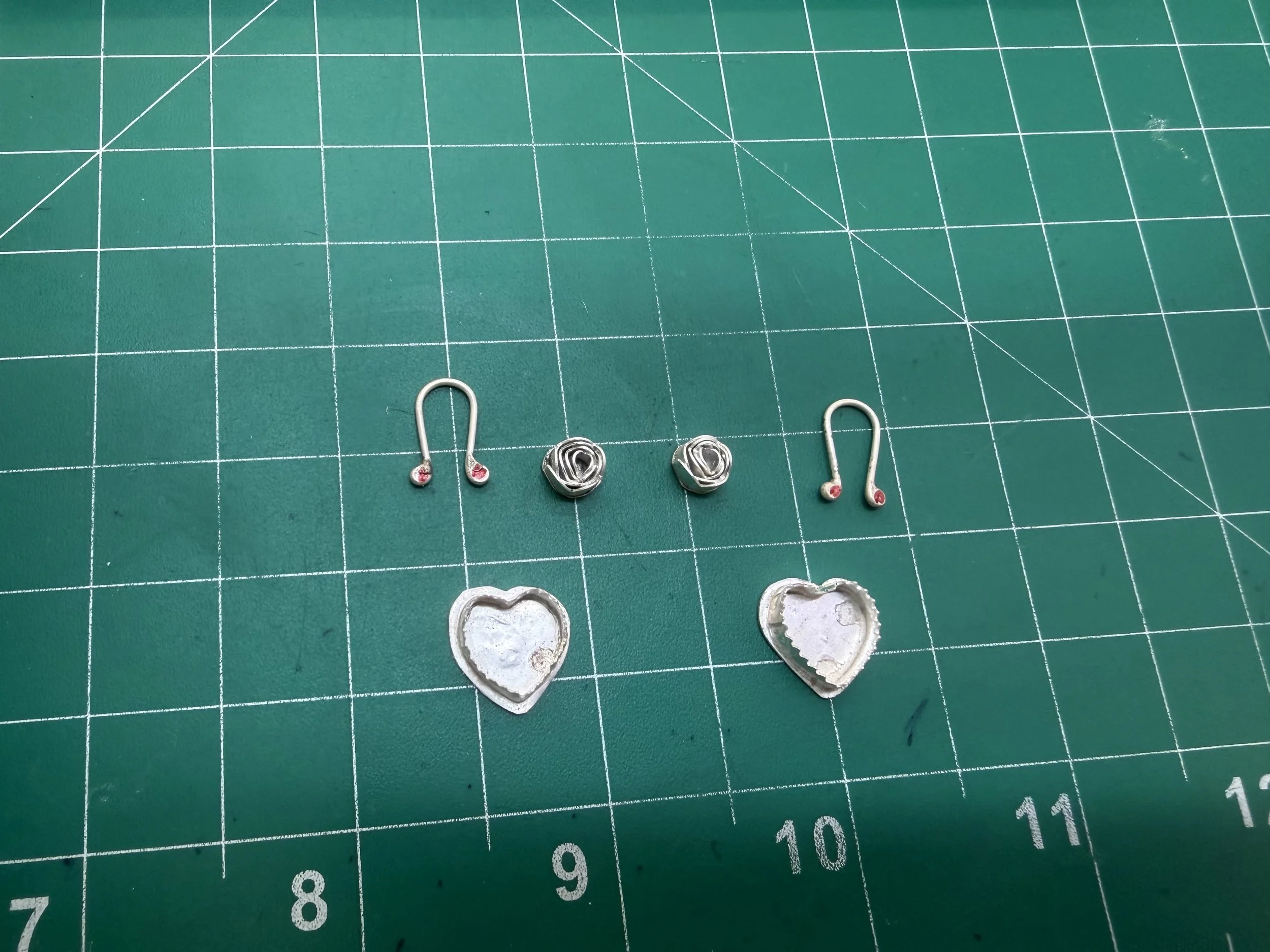 Earring components including ear wires, bezels, and heart shapes laid out during a jewelry workshop in Albuquerque