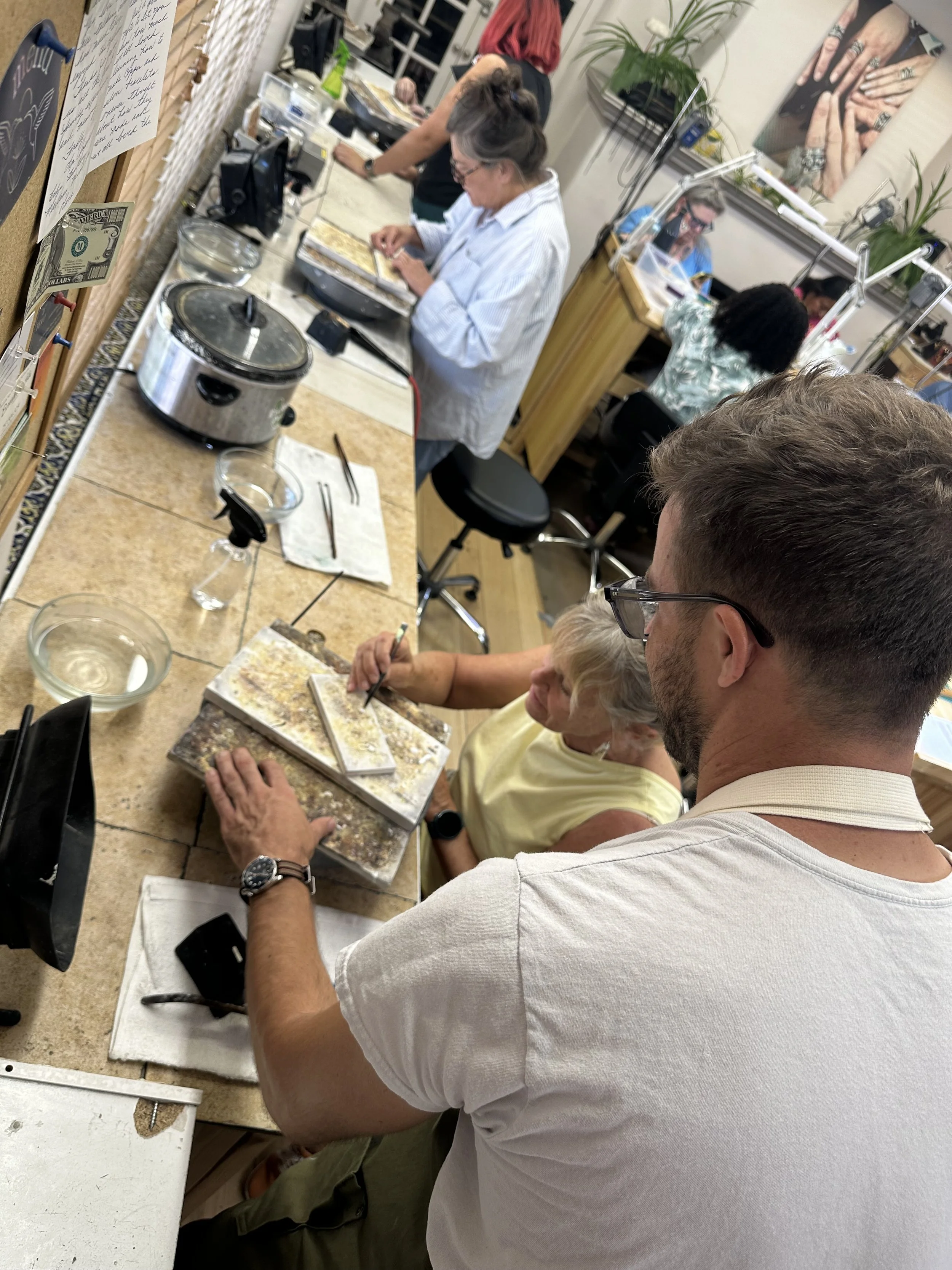 Students working at jewelry benches using tools and torches, jewelry making class Albuquerque