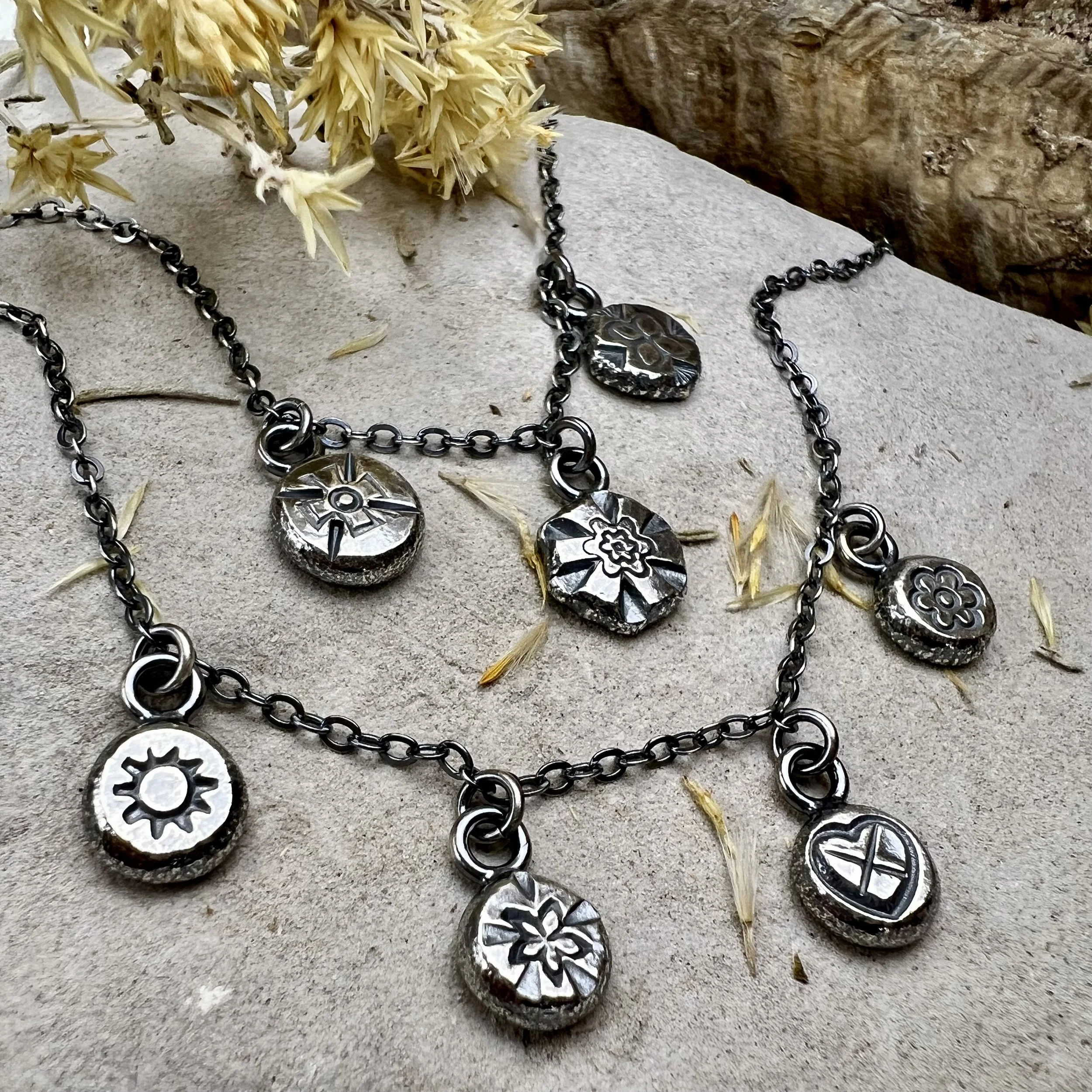 Jewelry making classes Albuquerque featuring finished silver charm necklaces.