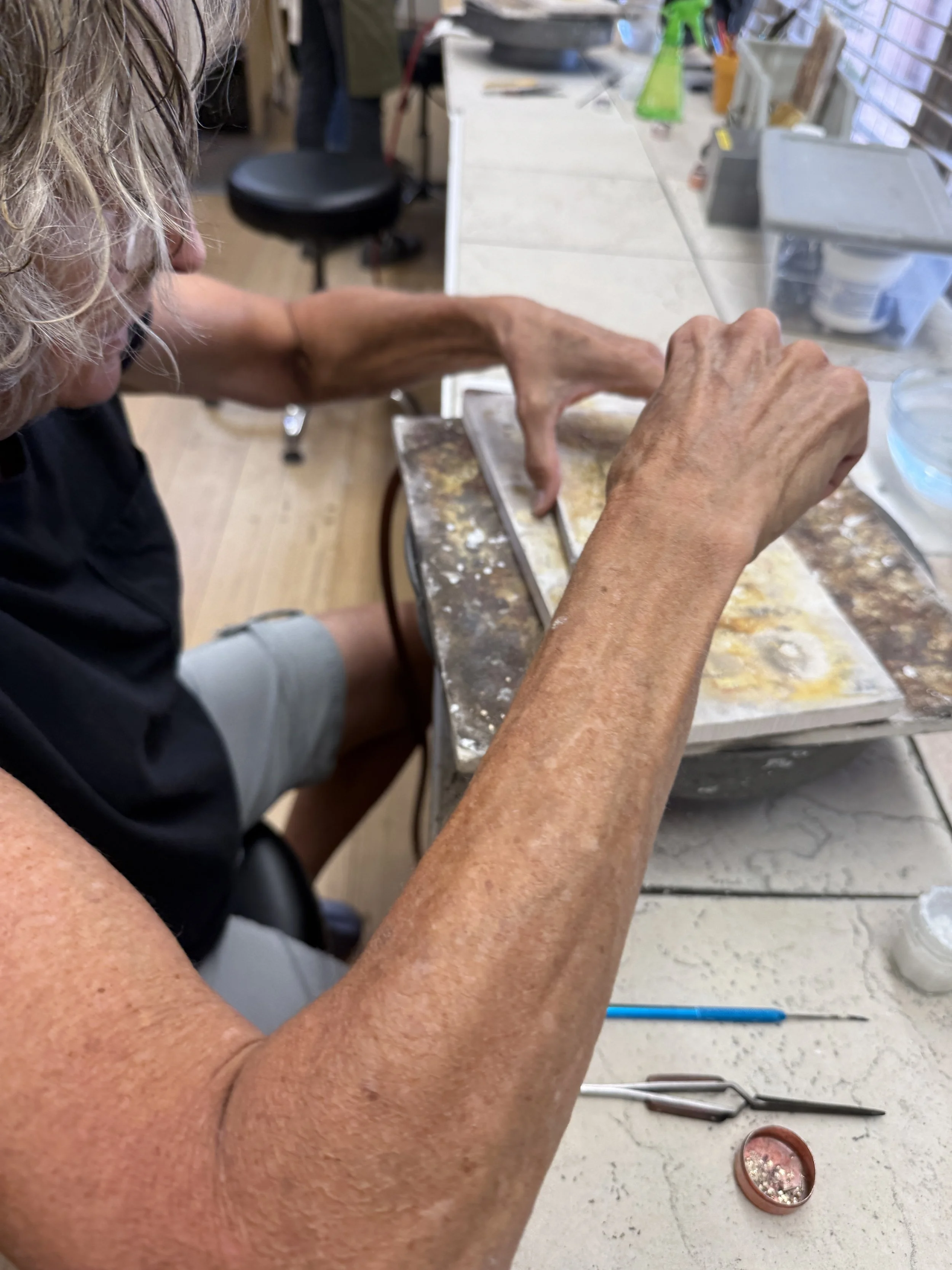 Student shaping silver on a jewelry workbench