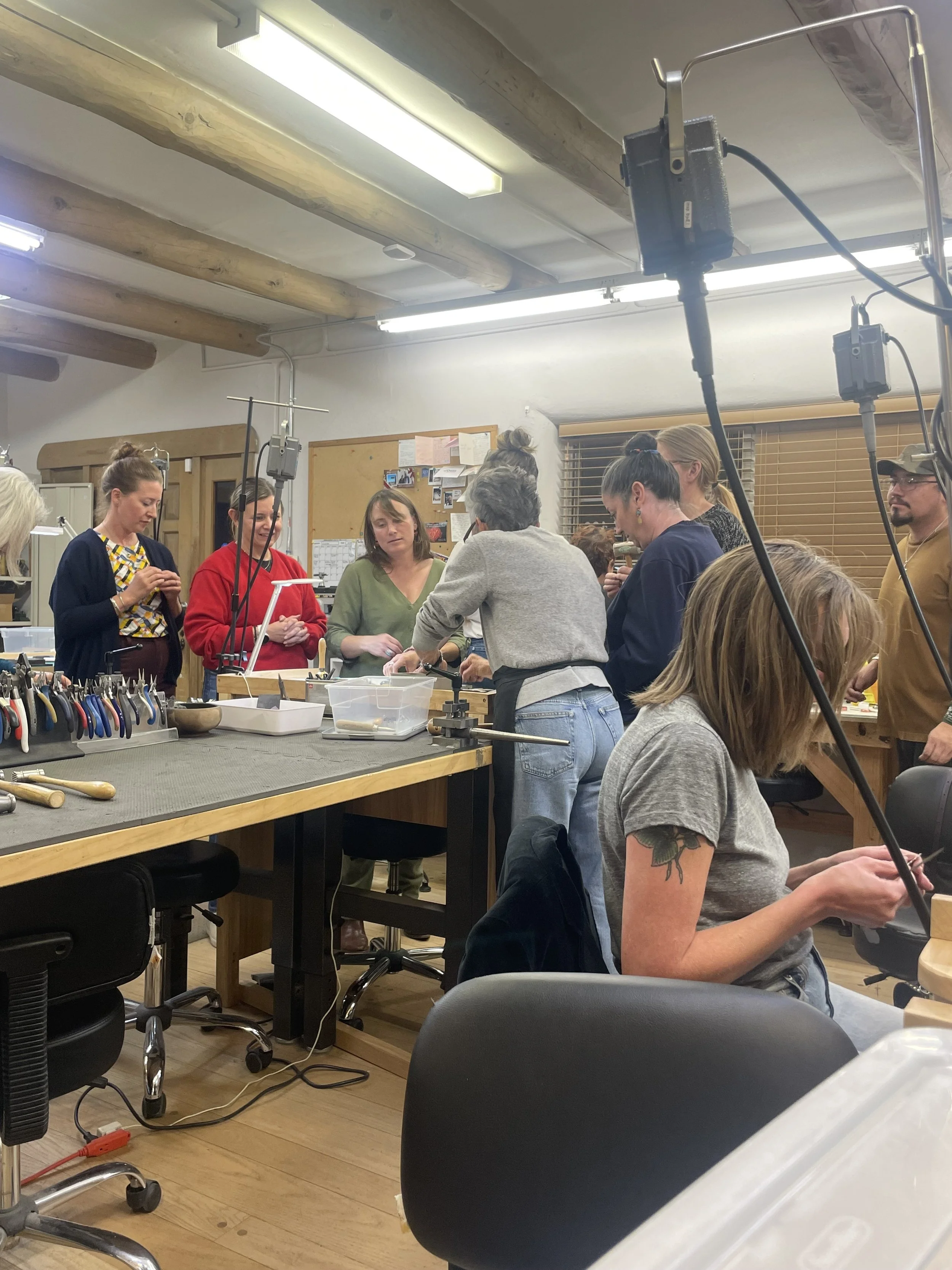 Instructor helping a student with a jewelry project at the workbench