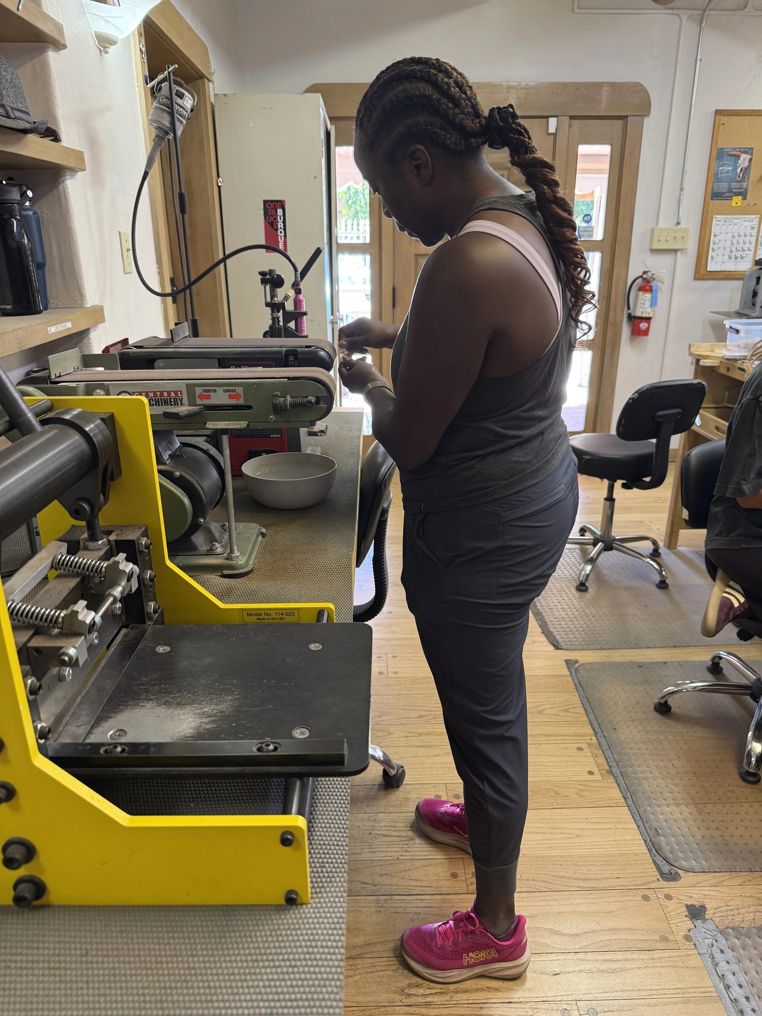 Student shaping jewelry at a sanding machine