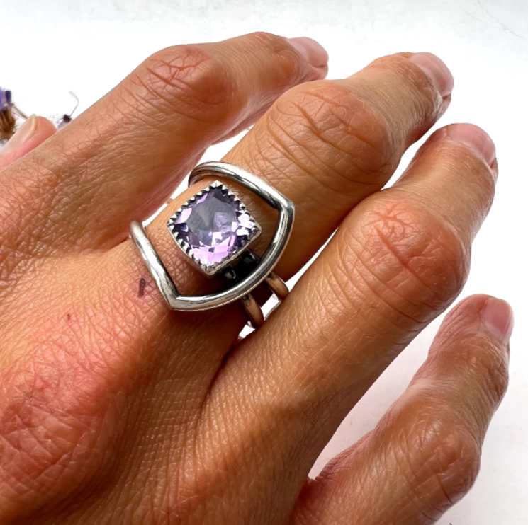 Handcrafted ring featuring a faceted purple worn on a hand