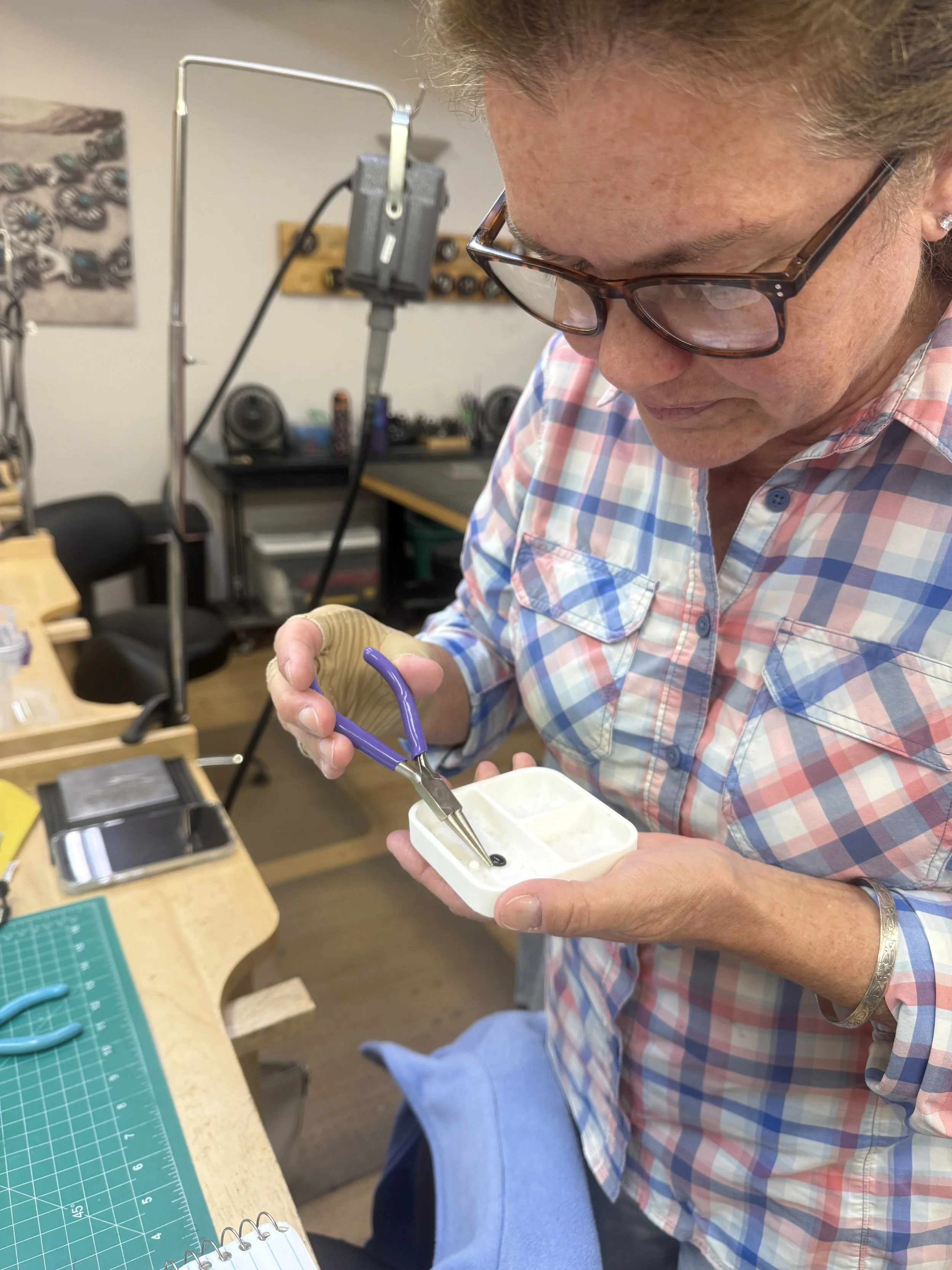 Student using pliers to work on a small jewelry component.