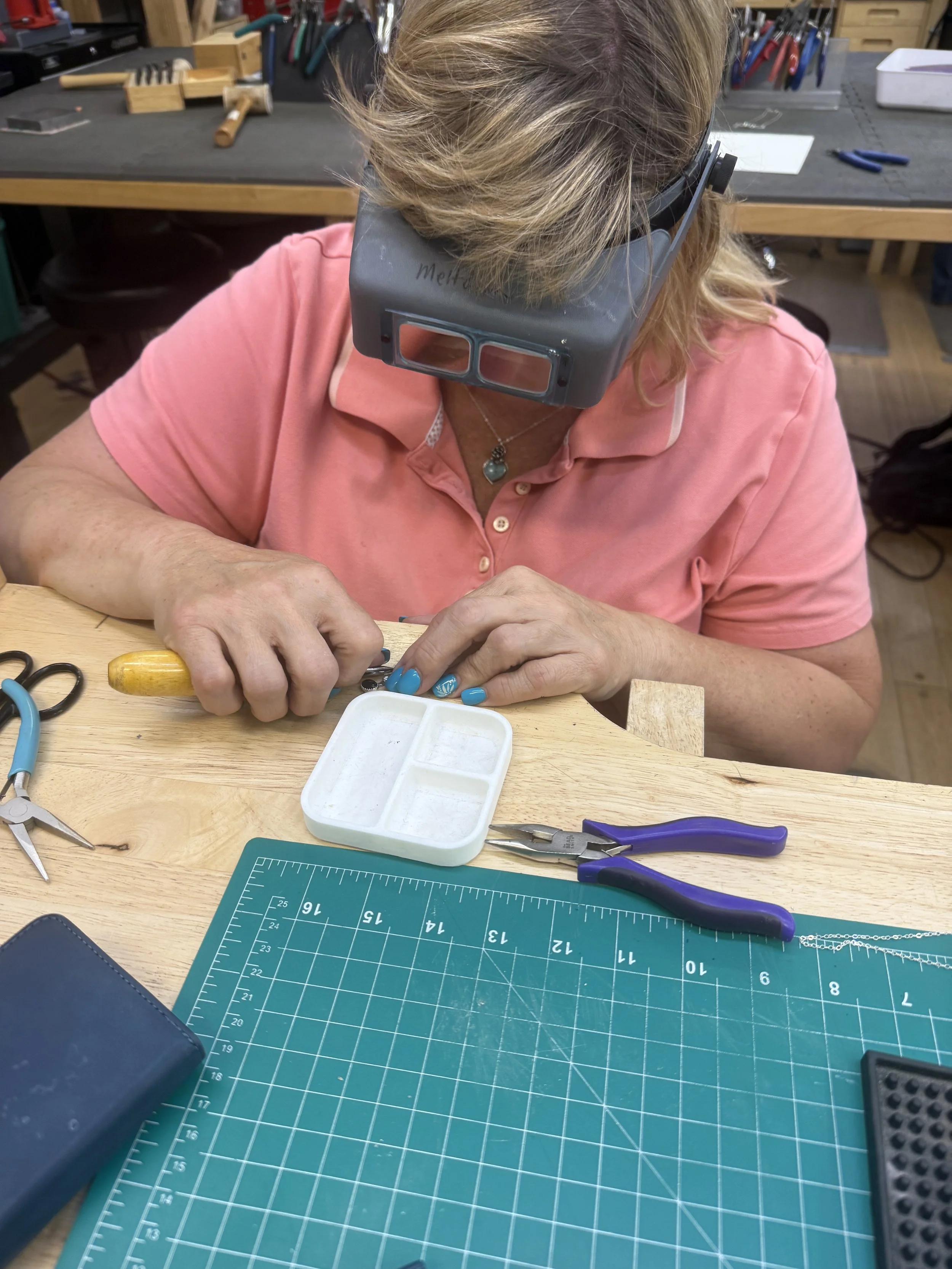 Student hammering a metal piece with a jewelry-making tool