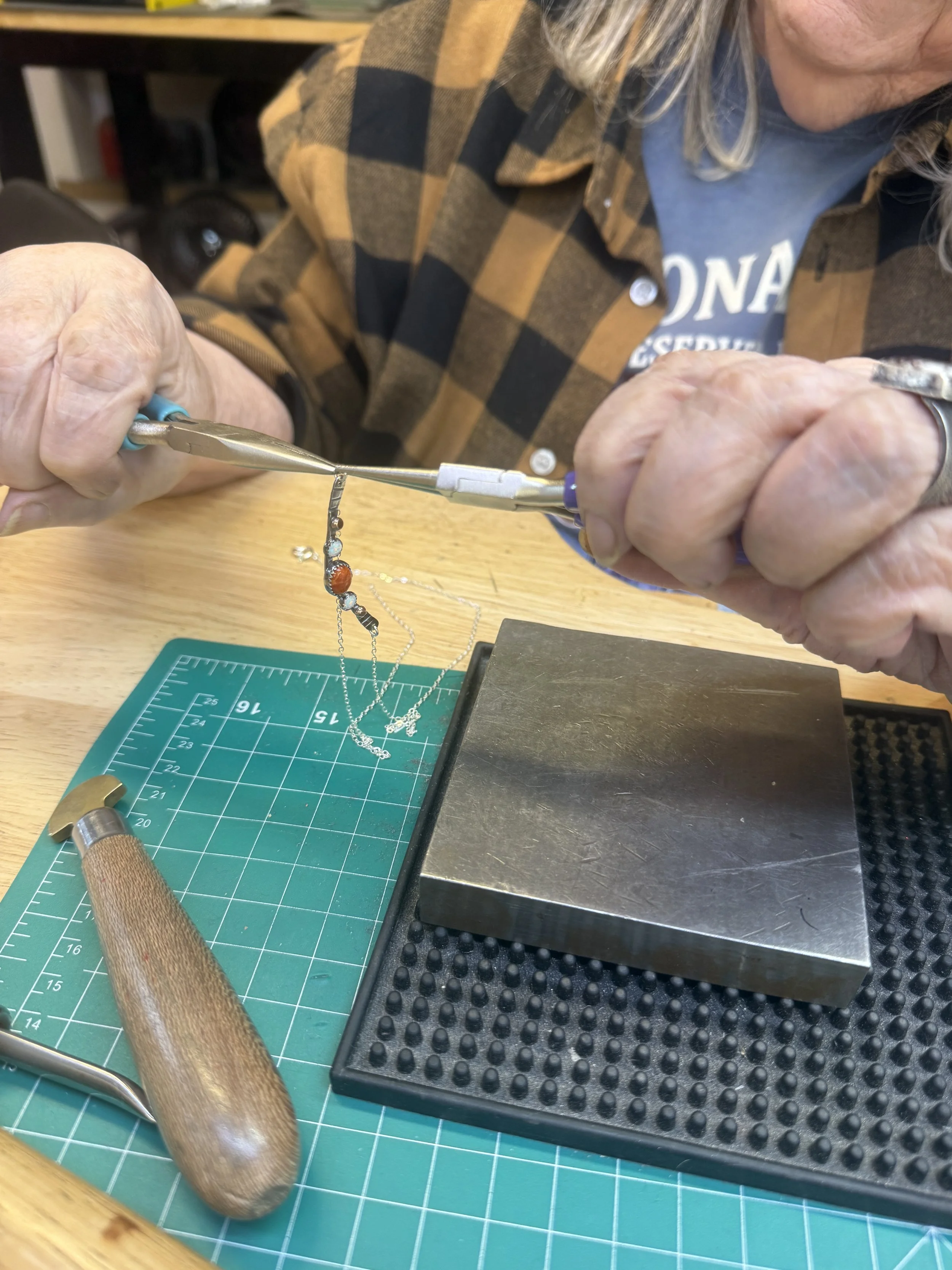 Student using pliers to adjust a necklace component.