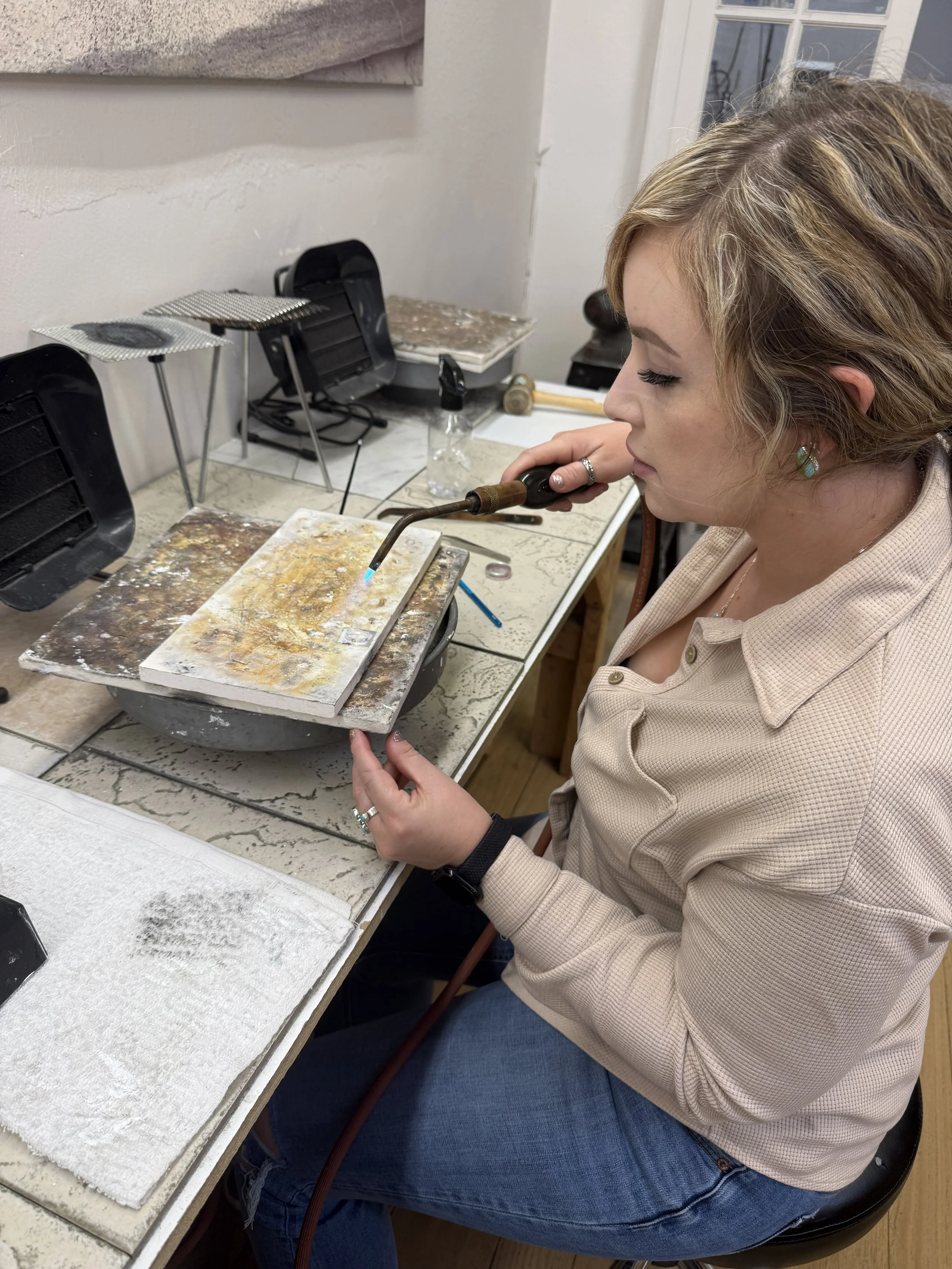 Student using a torch to solder a jewelry component.