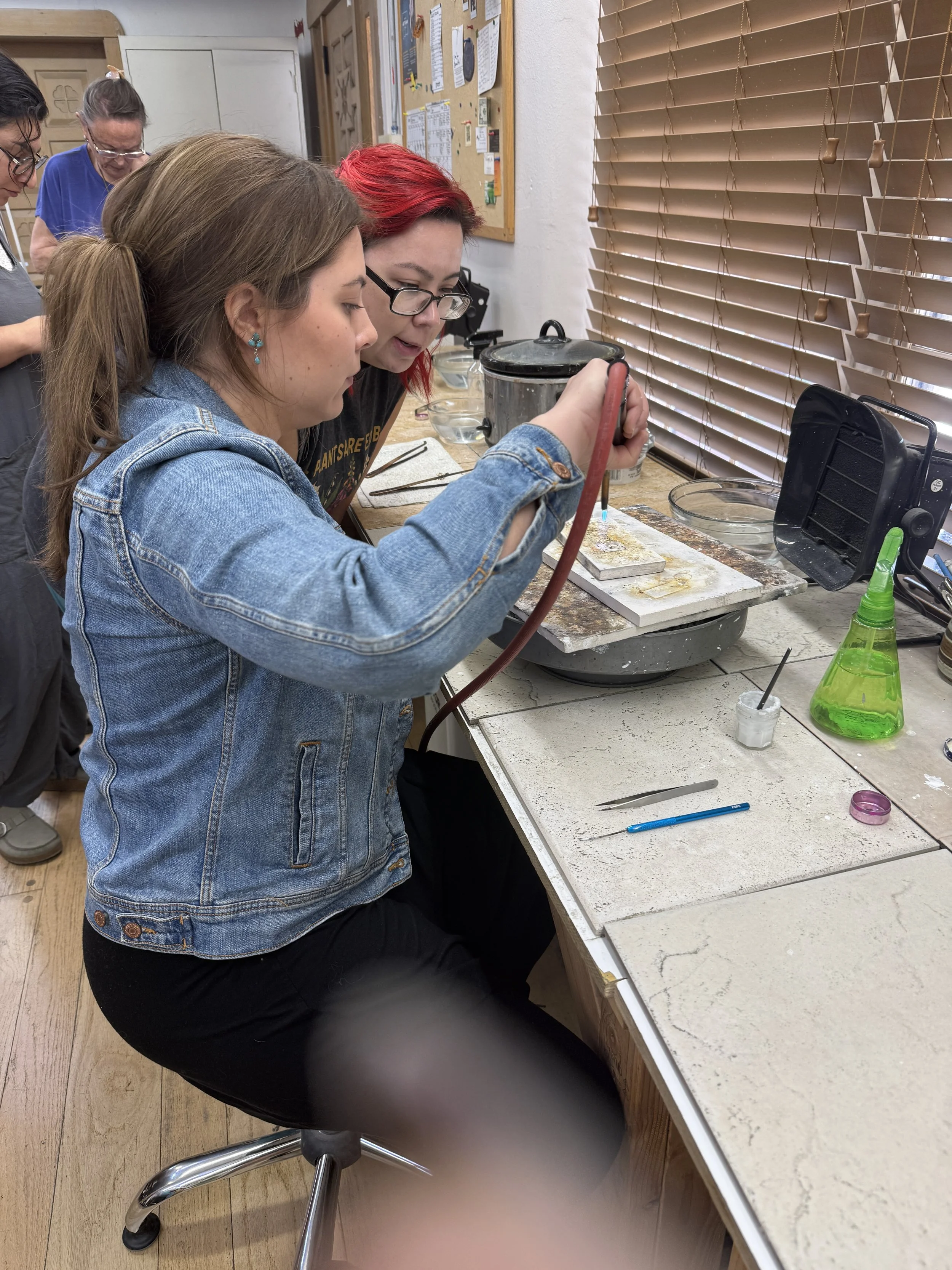Student soldering while instructor observes.