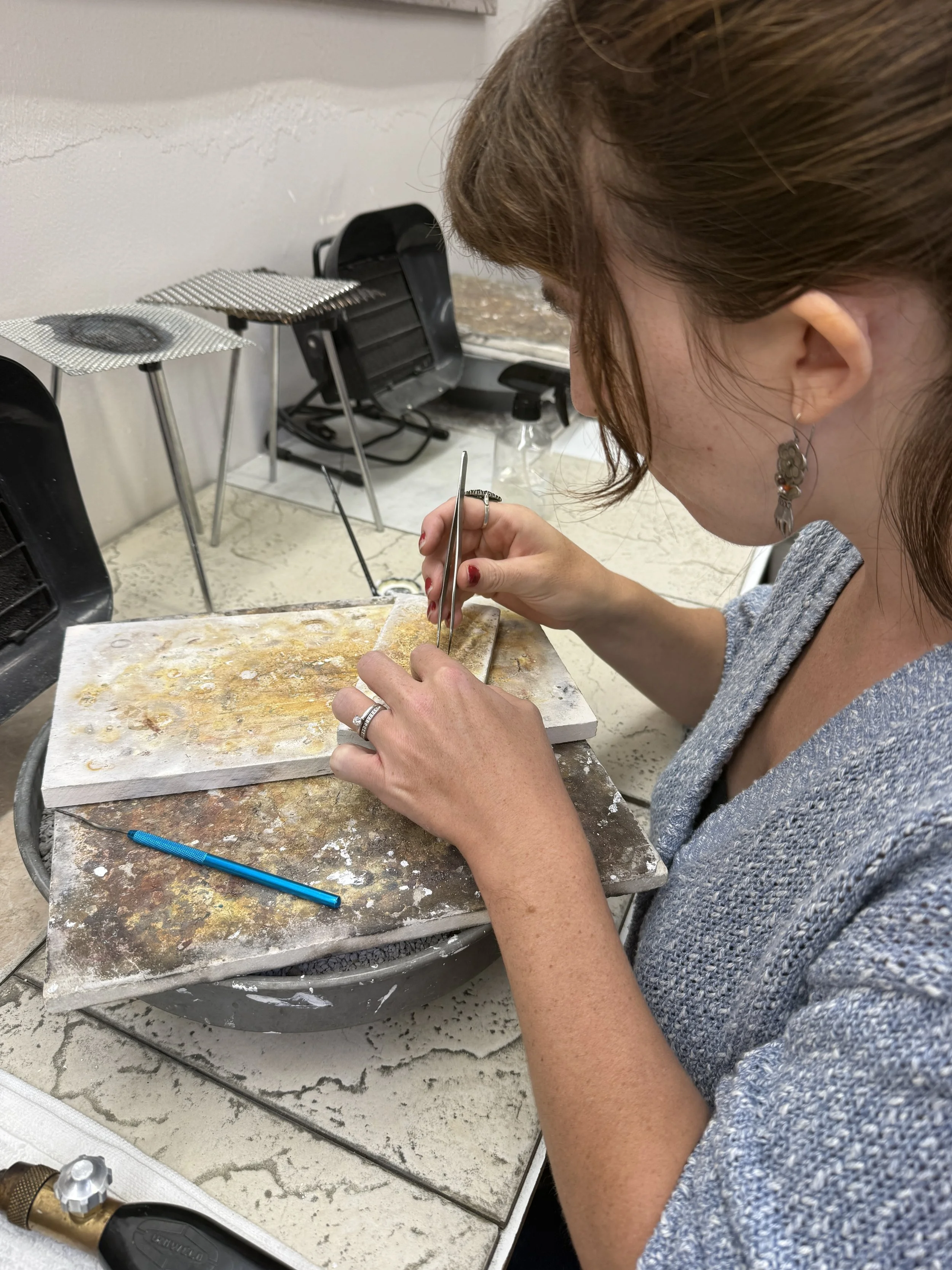 Student using tweezers to set a stone into jewelry.