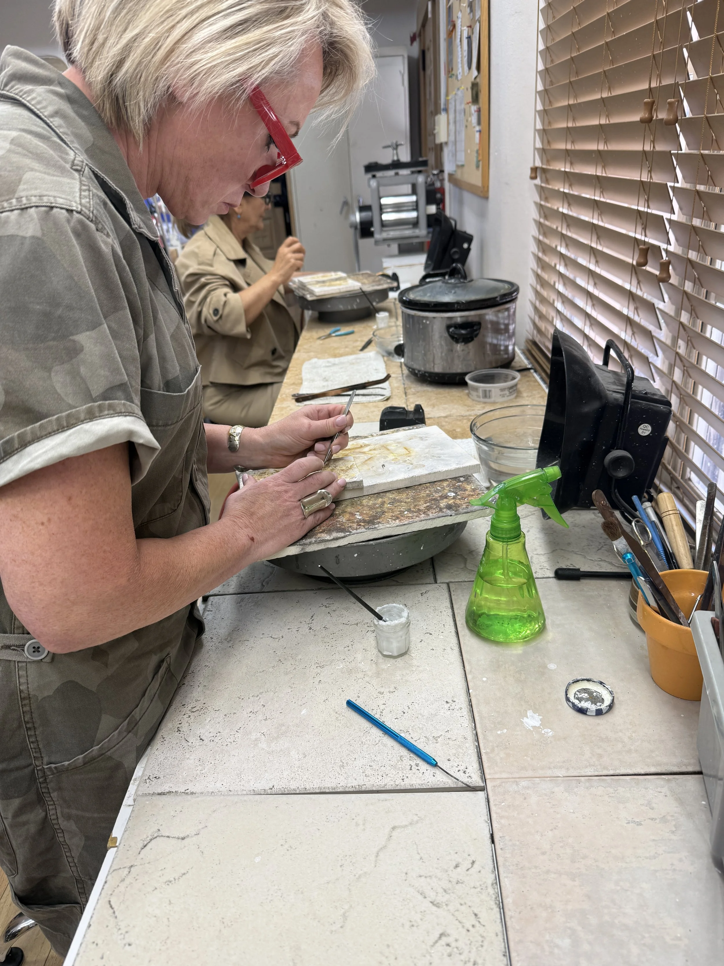 Student positioning a small jewelry component with tweezers.