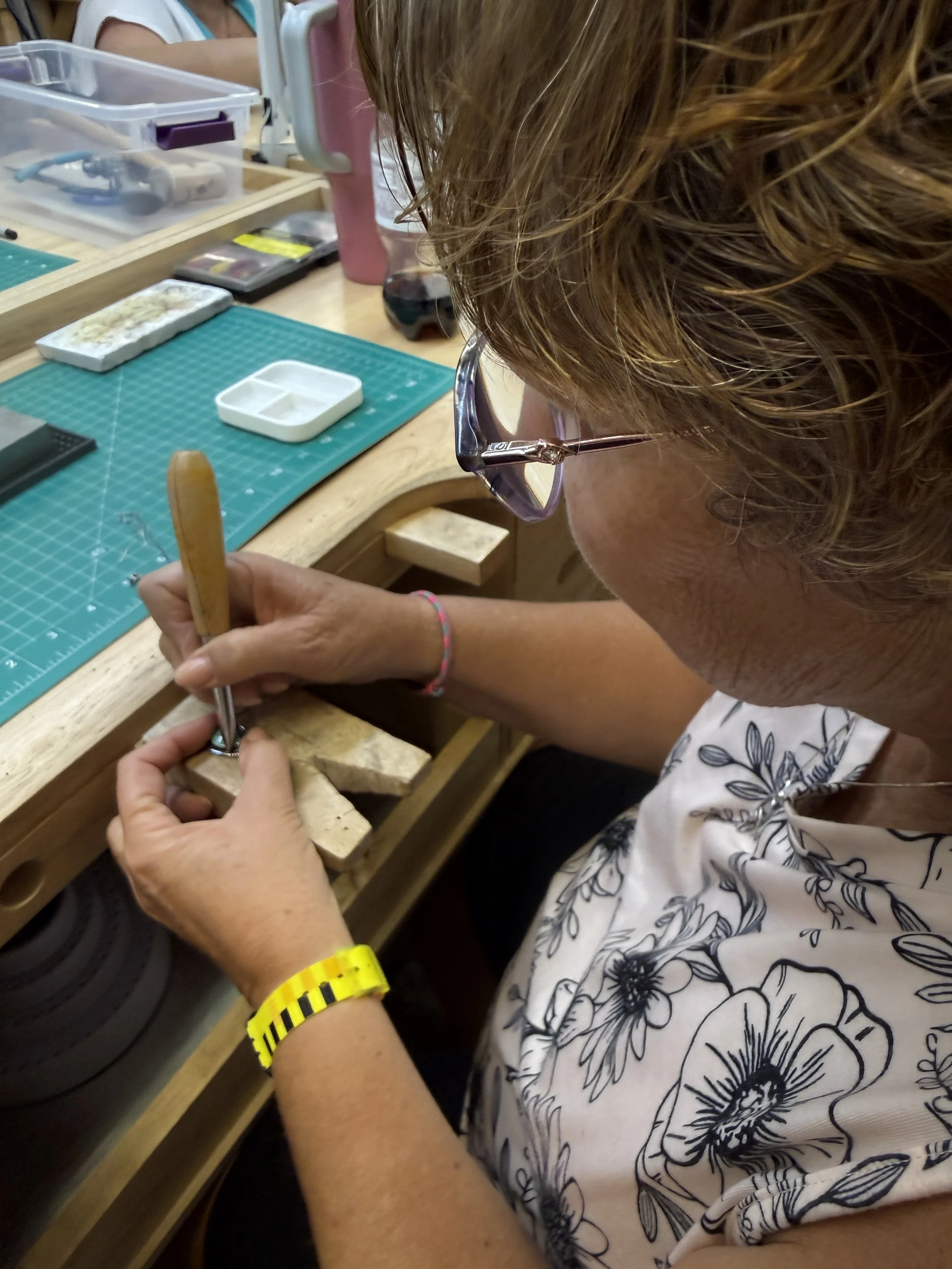 Student hammering a metal piece on a workbench.