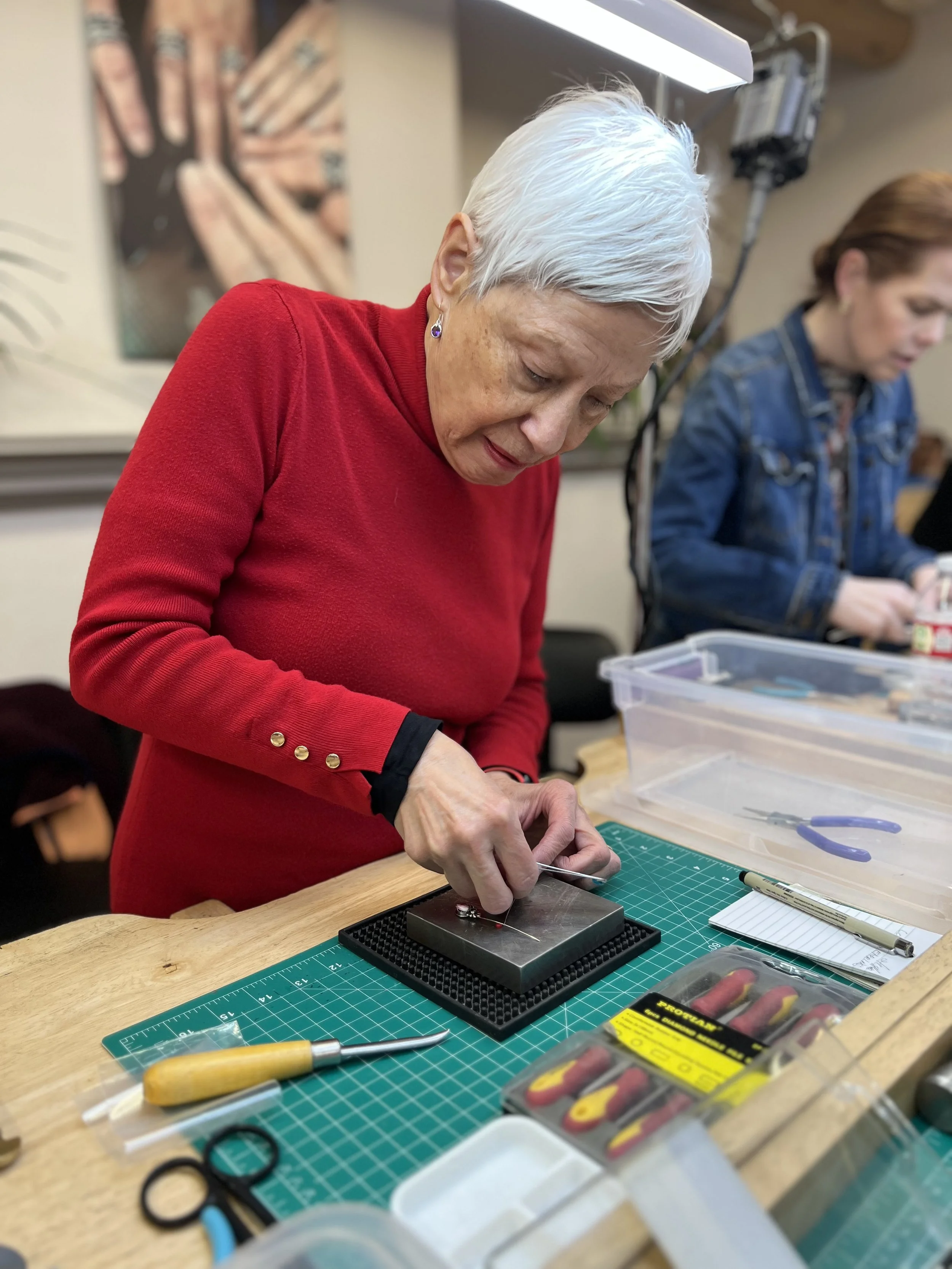 Student working independently at jewelry-making benches during a workshop at Meltdown Studio