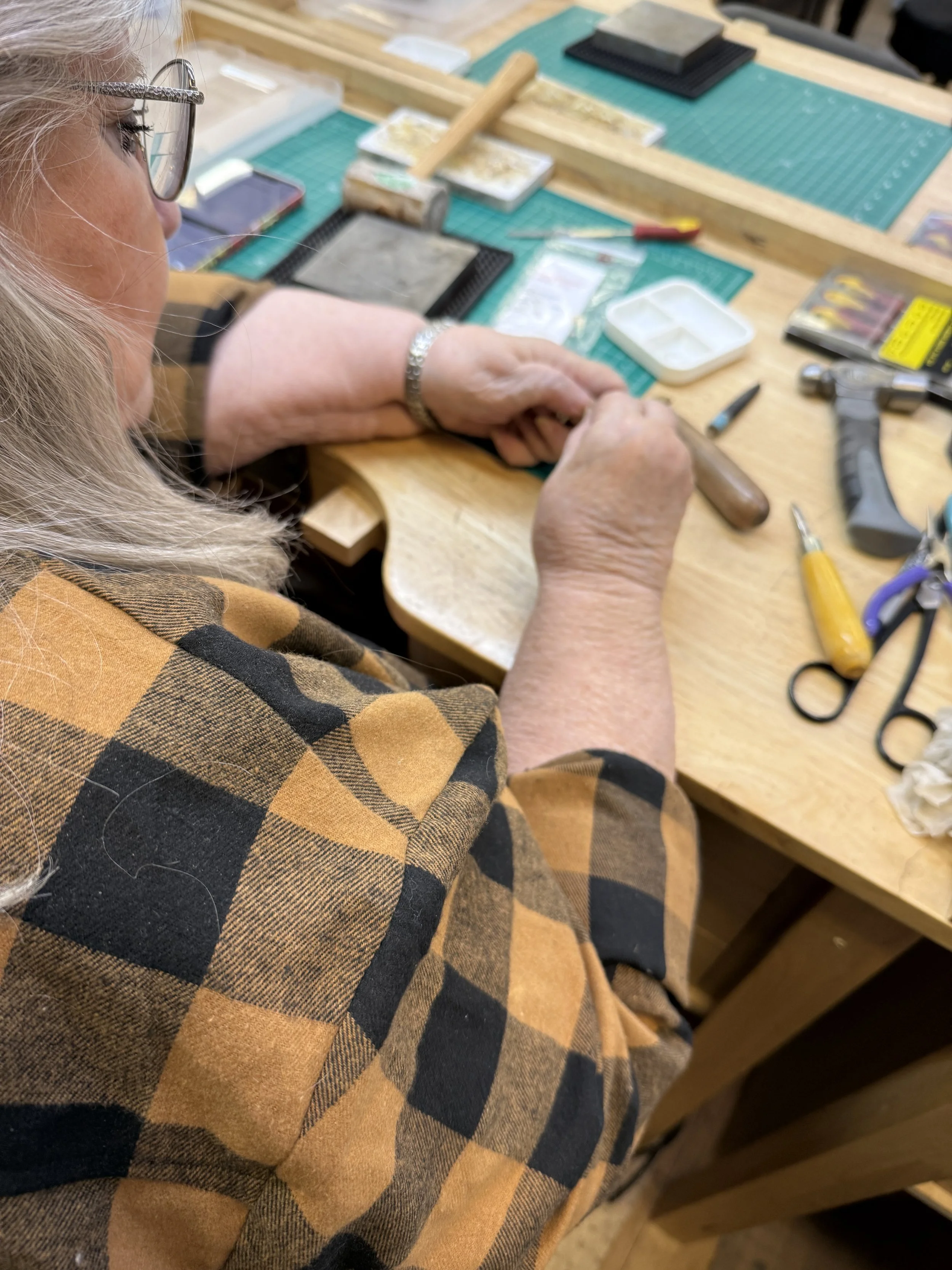 A student shaping a silver snake ring with hand tools