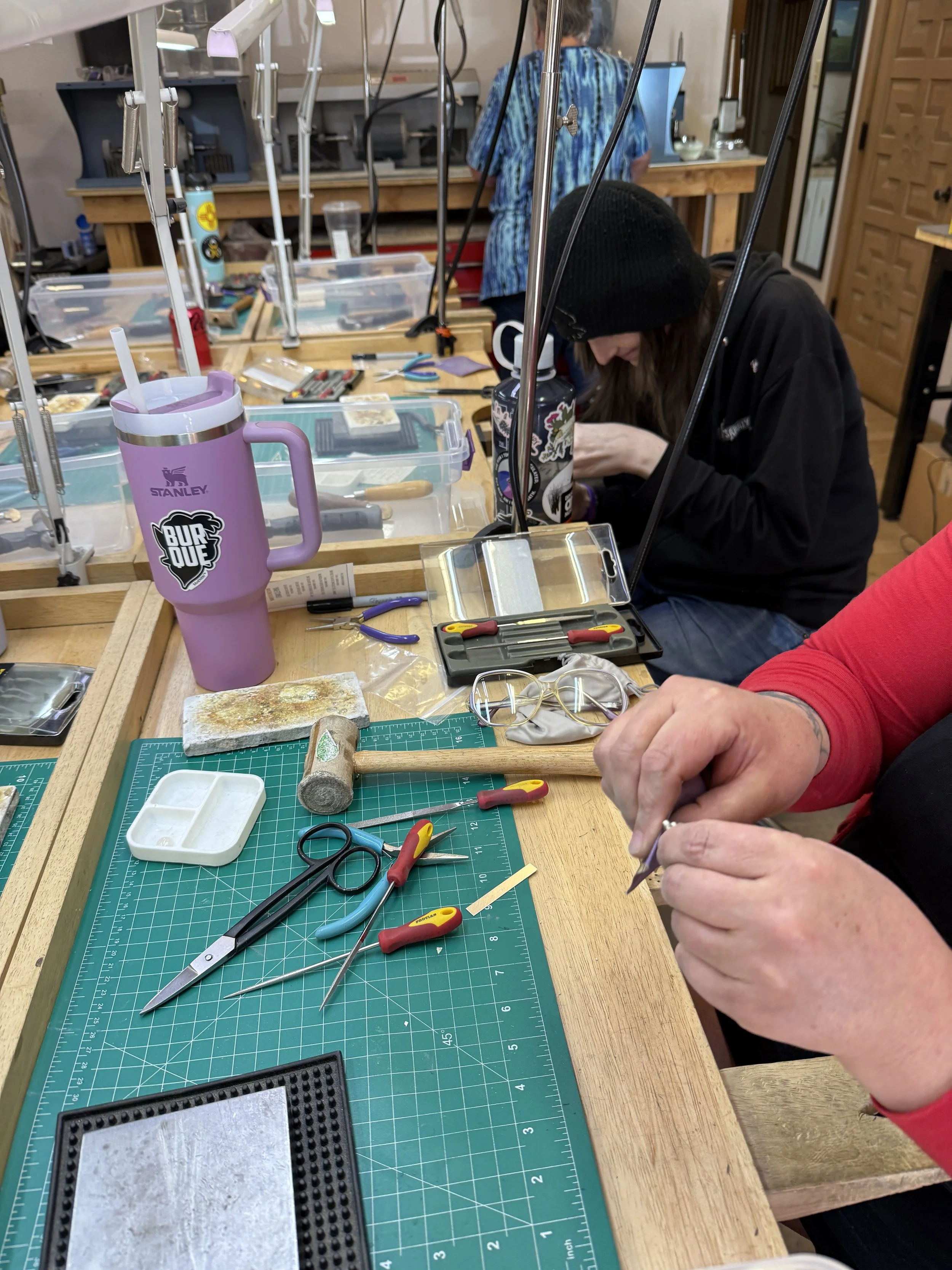 Close-up of a student carefully trimming a metal piece