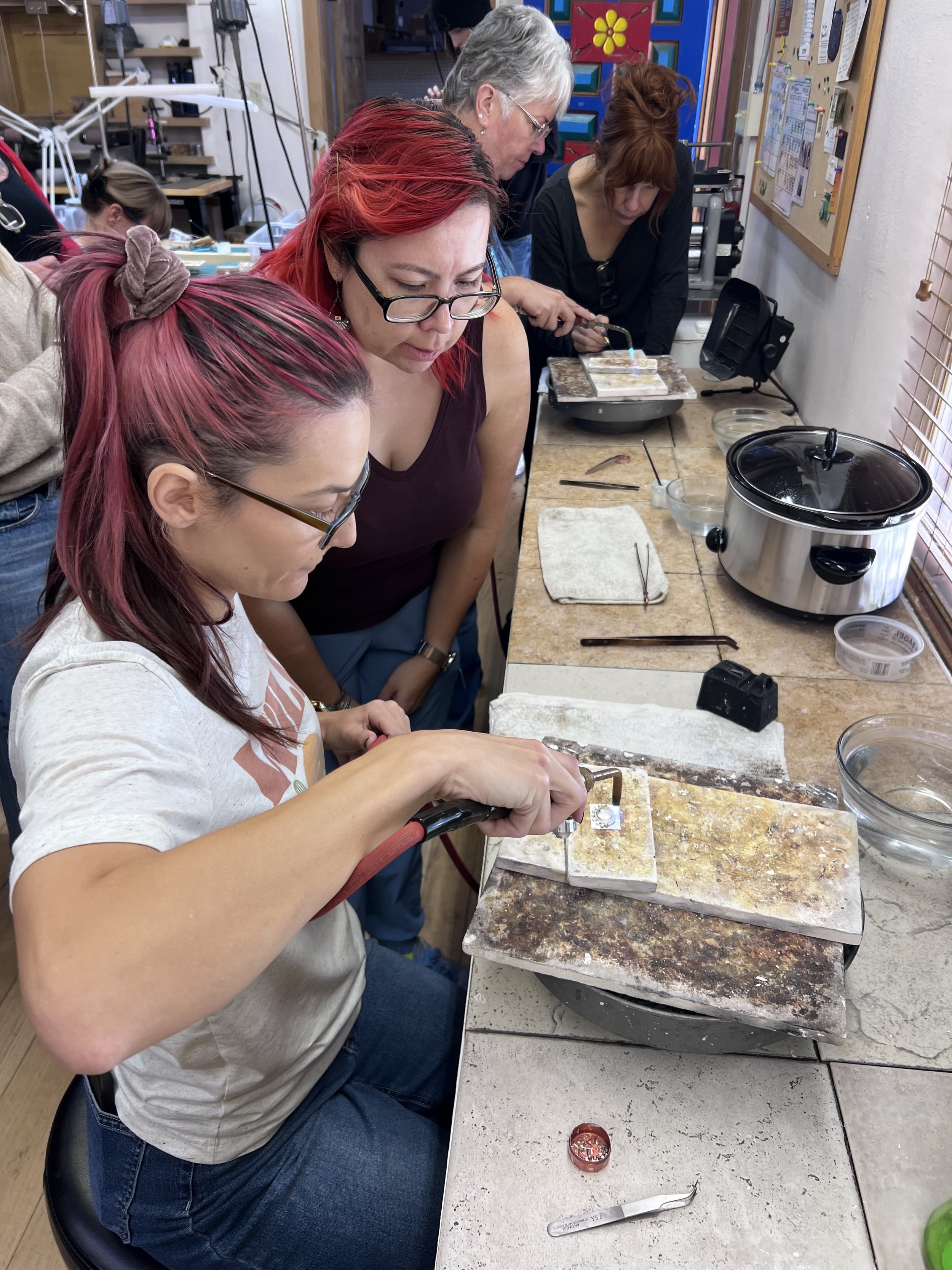 A student soldering the decorative silver details of an Oracle Ring