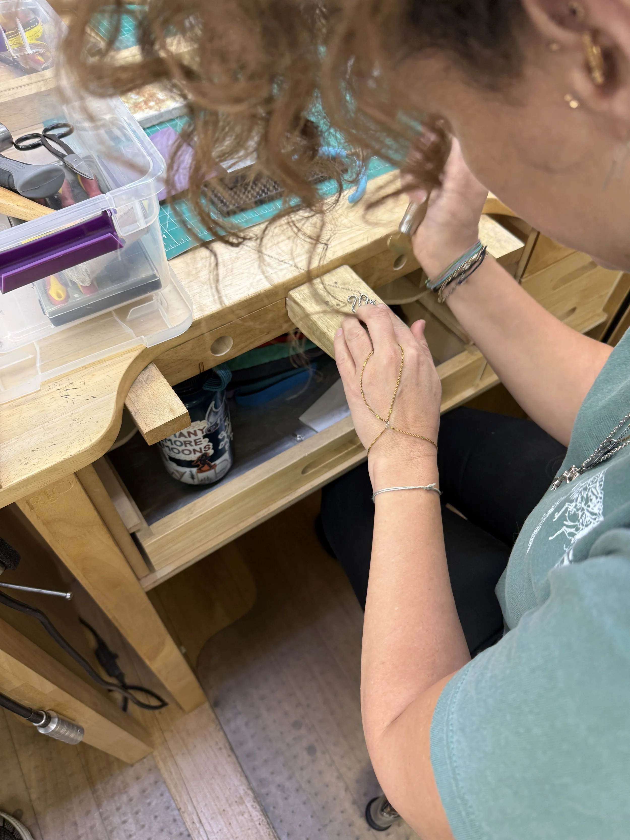 Student shaping a small silver jewelry component by hand