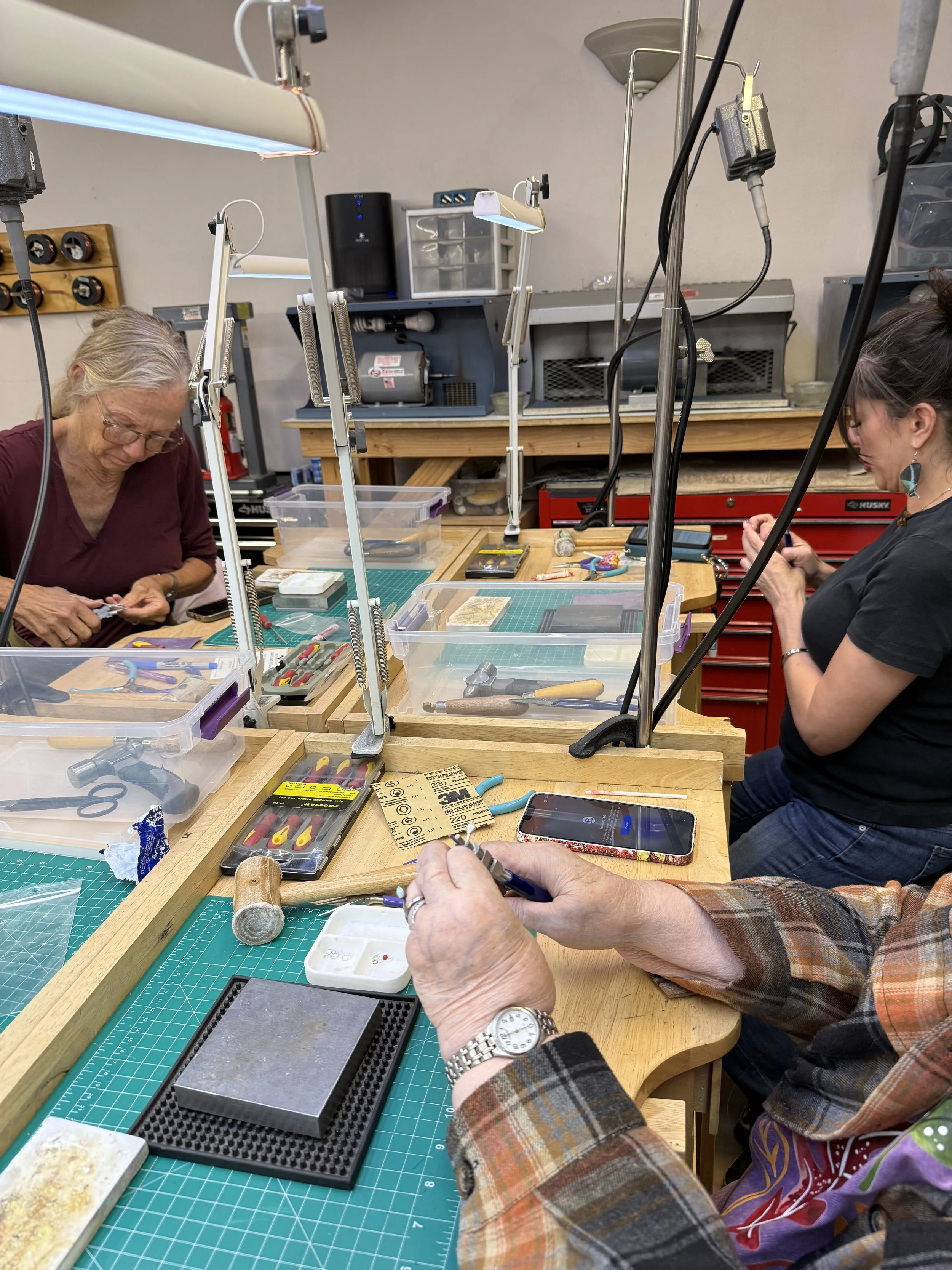 Students working at jewelry benches during a snake necklace class at Meltdown Studio