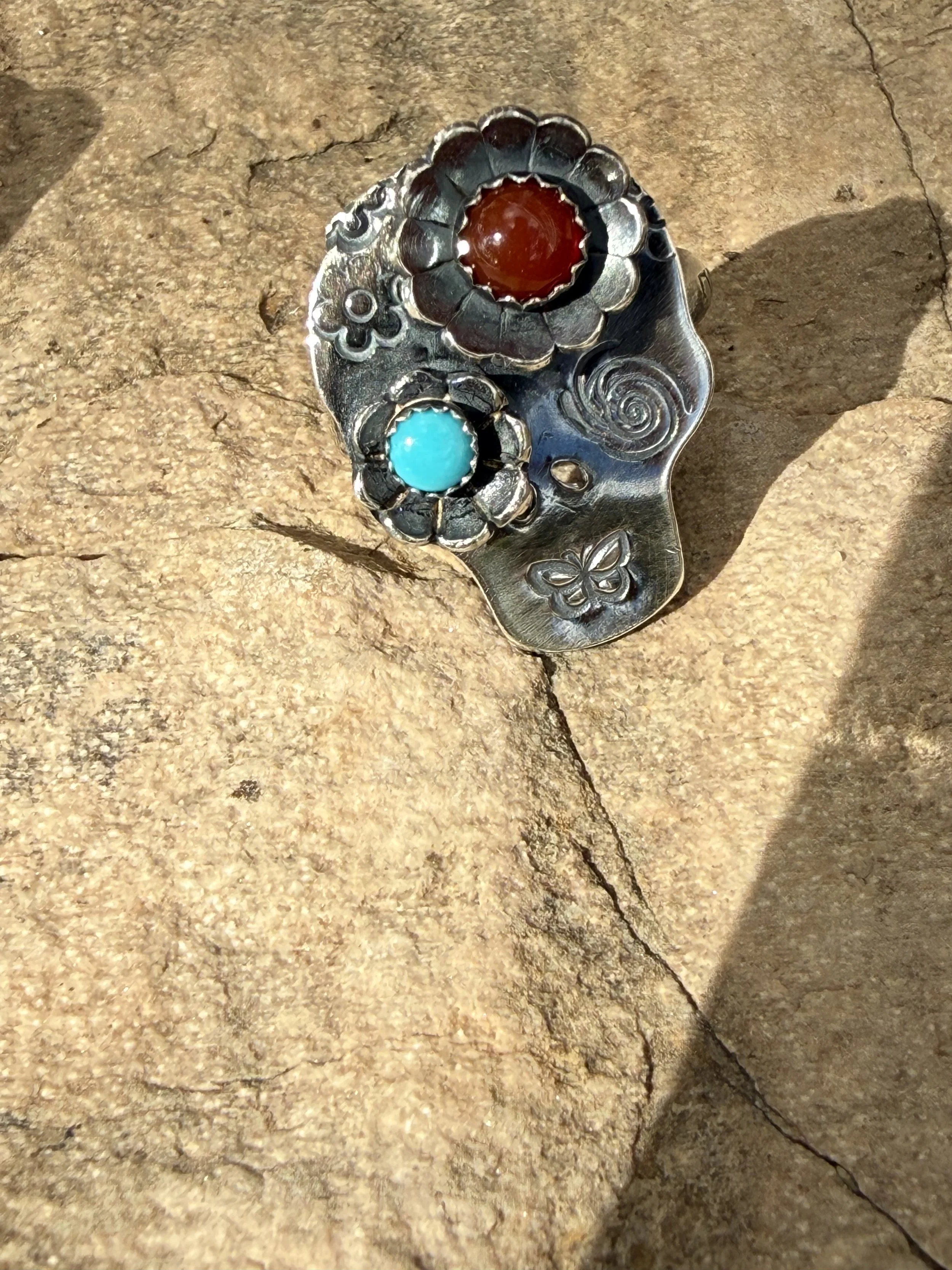Handcrafted ring with red and turquoise-colored stones and raised floral details