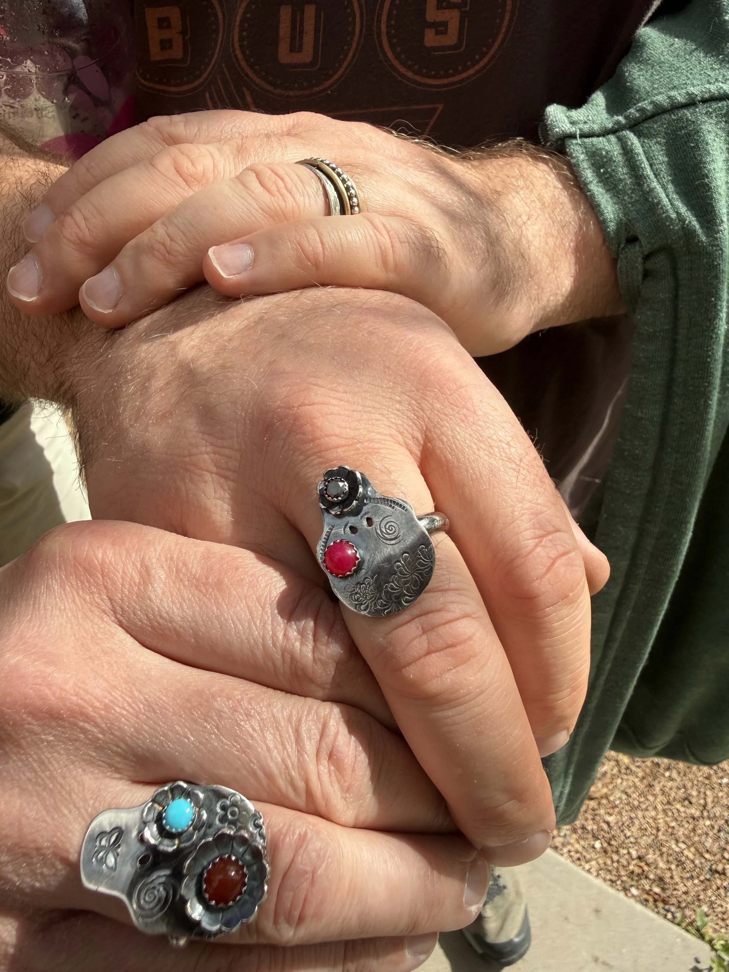 Students’ hands displaying handcrafted silver statement rings with colorful stone settings