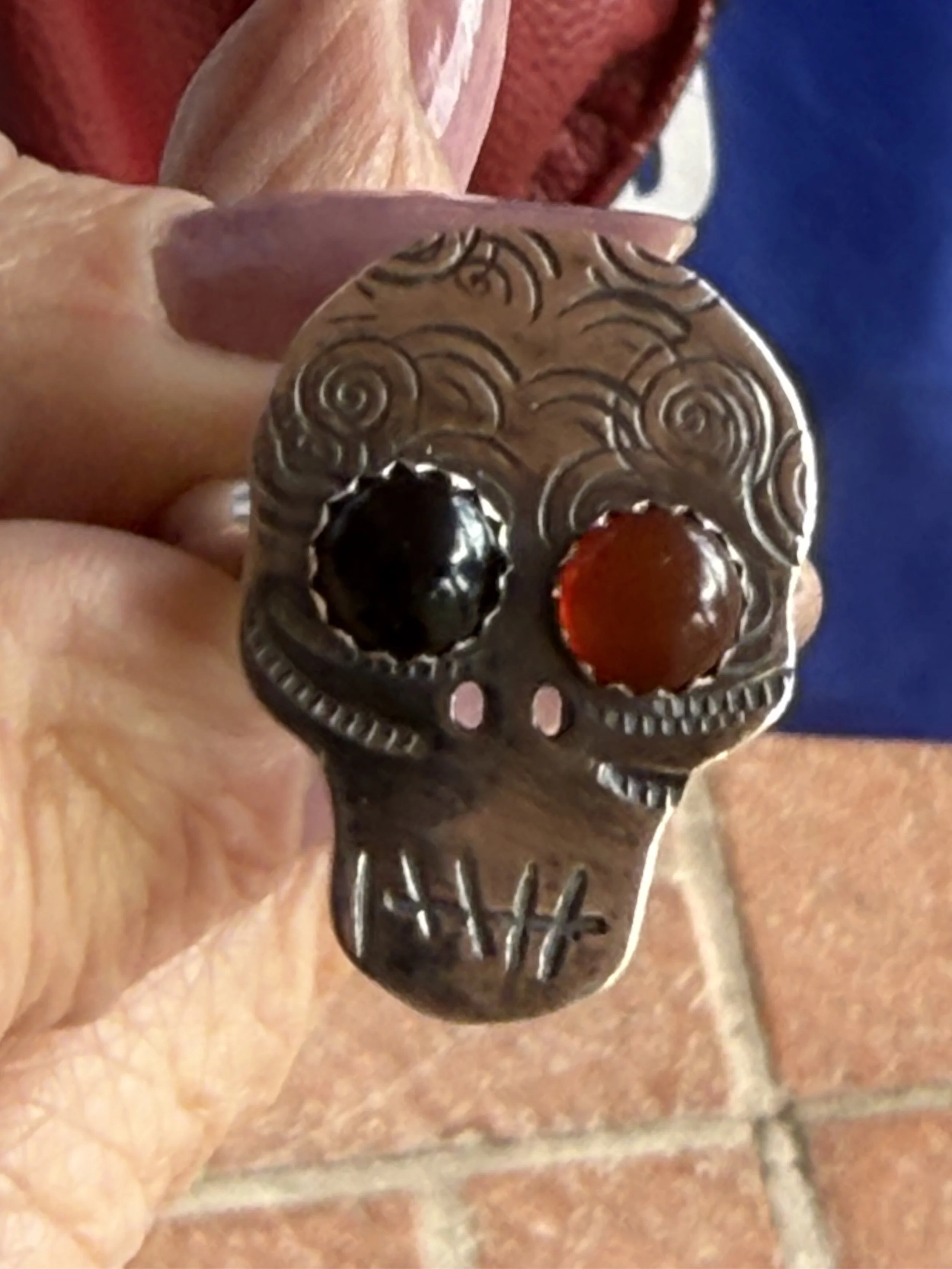 Handmade ring with dark and red stones, engraved swirls, and skull details
