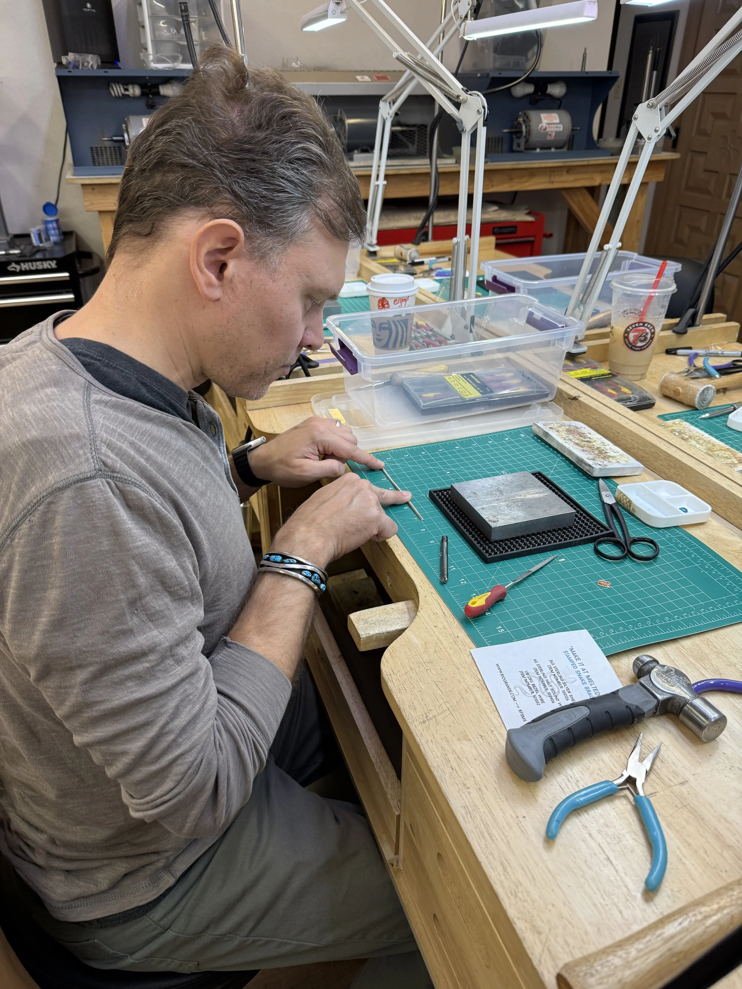A student measuring and working with a thin metal rod on a cutting mat