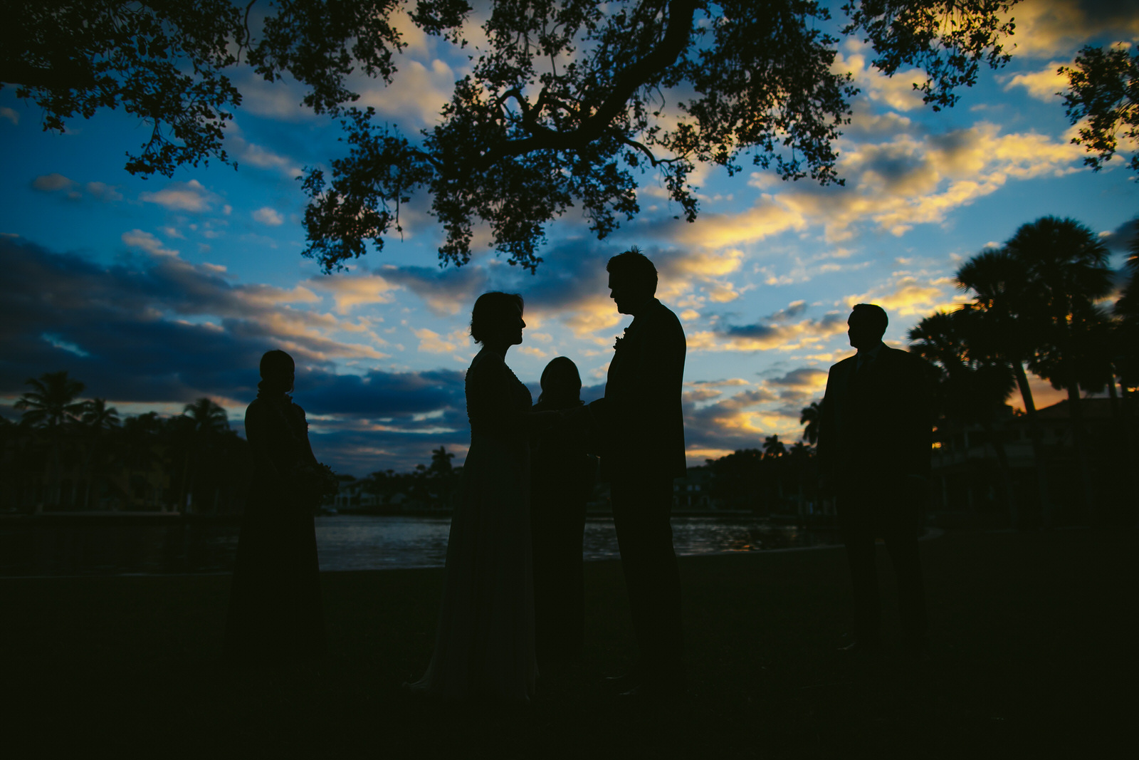 Gorgeous skies during a sunset ceremony in Downtown Fort Lauderdale. Blue skies and silhouettes of bride groom and wedding party can be seen.