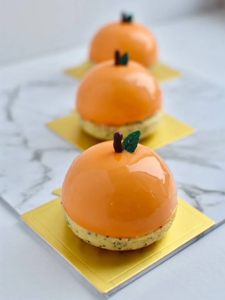 ORANGE AND POPPY SEED Orange and poppy seed sponge centre and base, cream cheese mousse, orange curd, mirror glaze. $6.90 each Minimum Order Quantity : 8