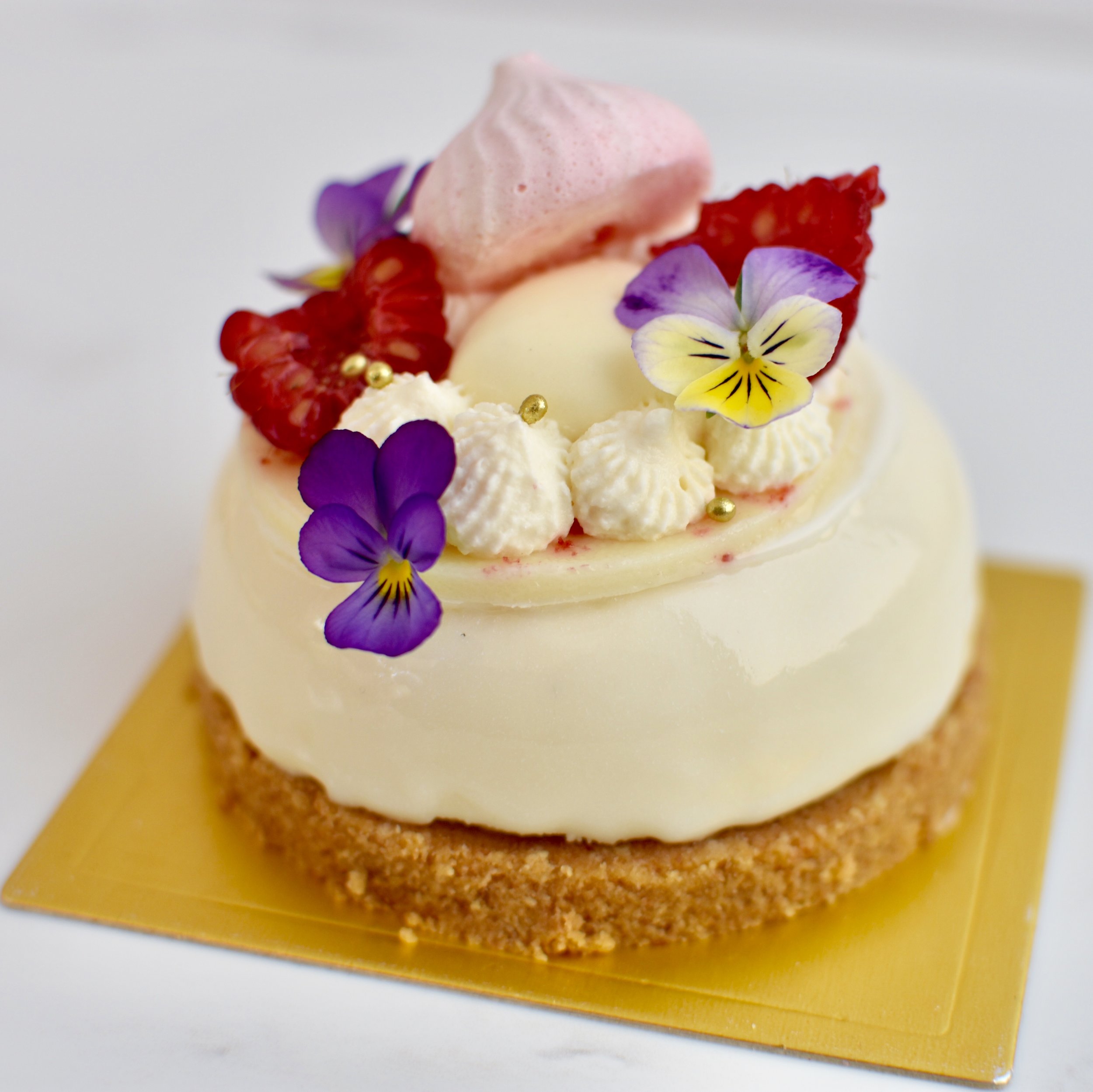 RASPBERRY DREAM Biscuit base, vanilla cheesecake, raspberry compote, white chocolate glaze, white chocolate disc, raspberries. $7.50 each Minimum Order Quantity : 10