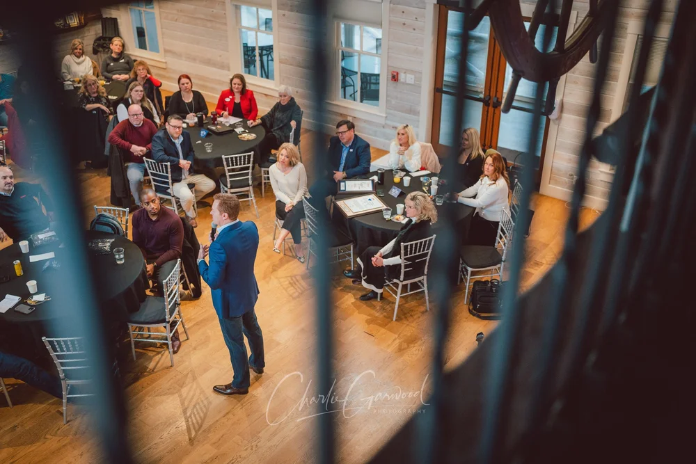 Event guests gathered around tables listening to a speaker